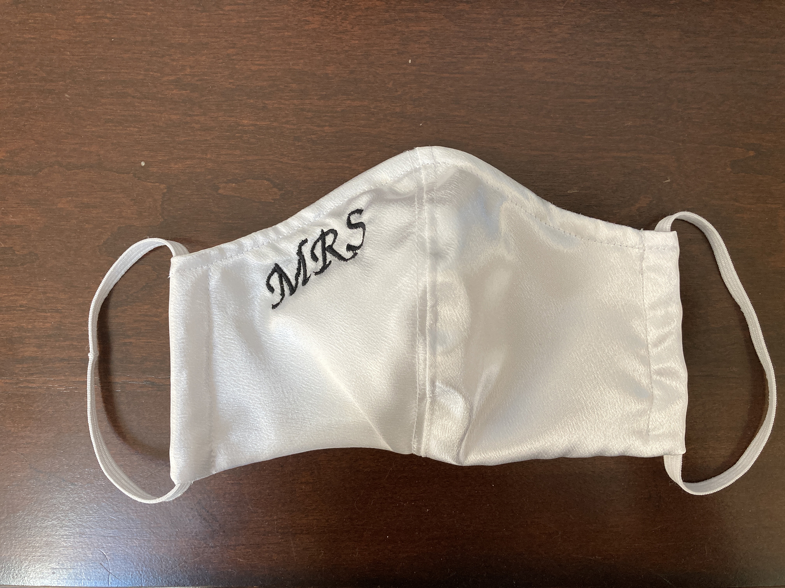 White satin mask with "MRS" embroidered in black thread