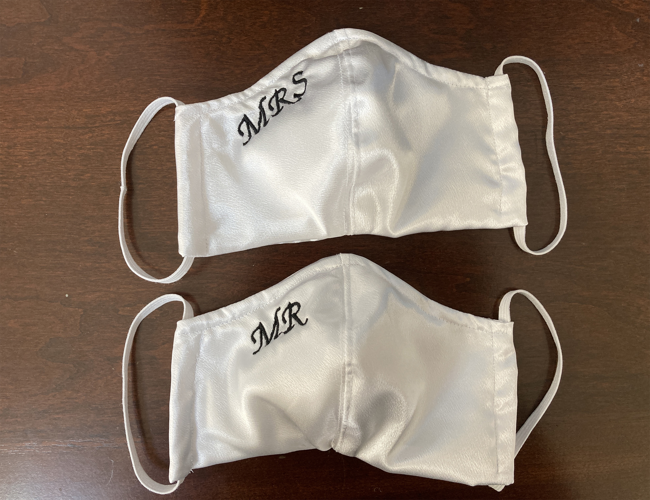 Photo of two white satin face masks embroidered with MR and MRS