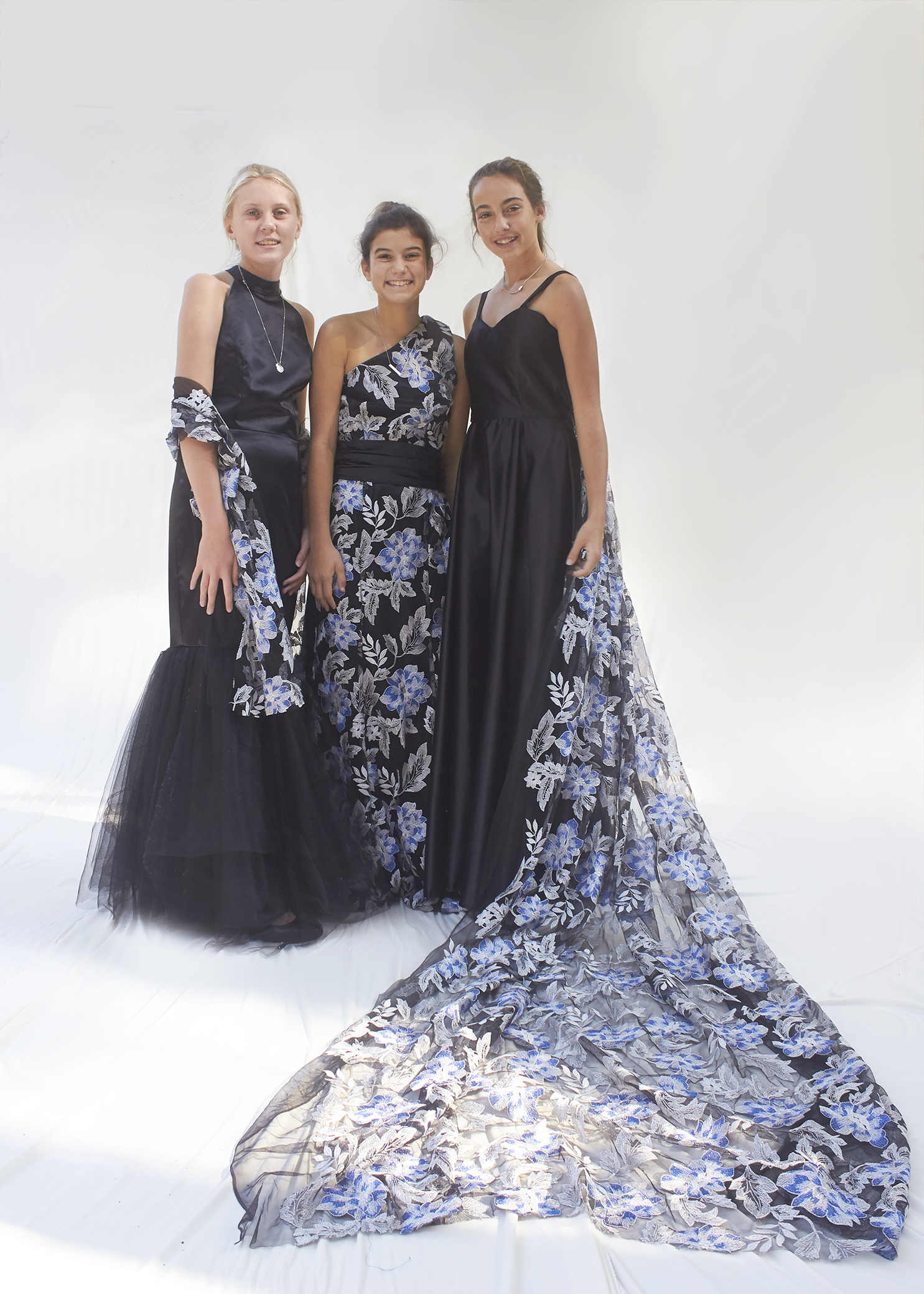 Three girls stand together with black and silver gowns on