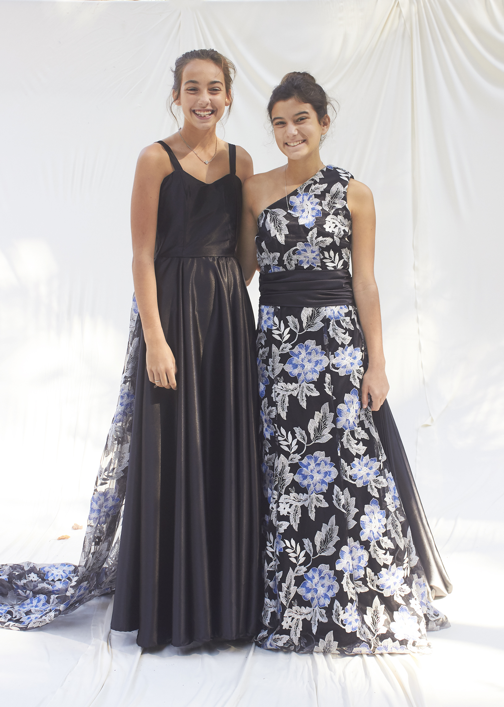 Two girls in black evening gowns with silver and blue brocade overlay