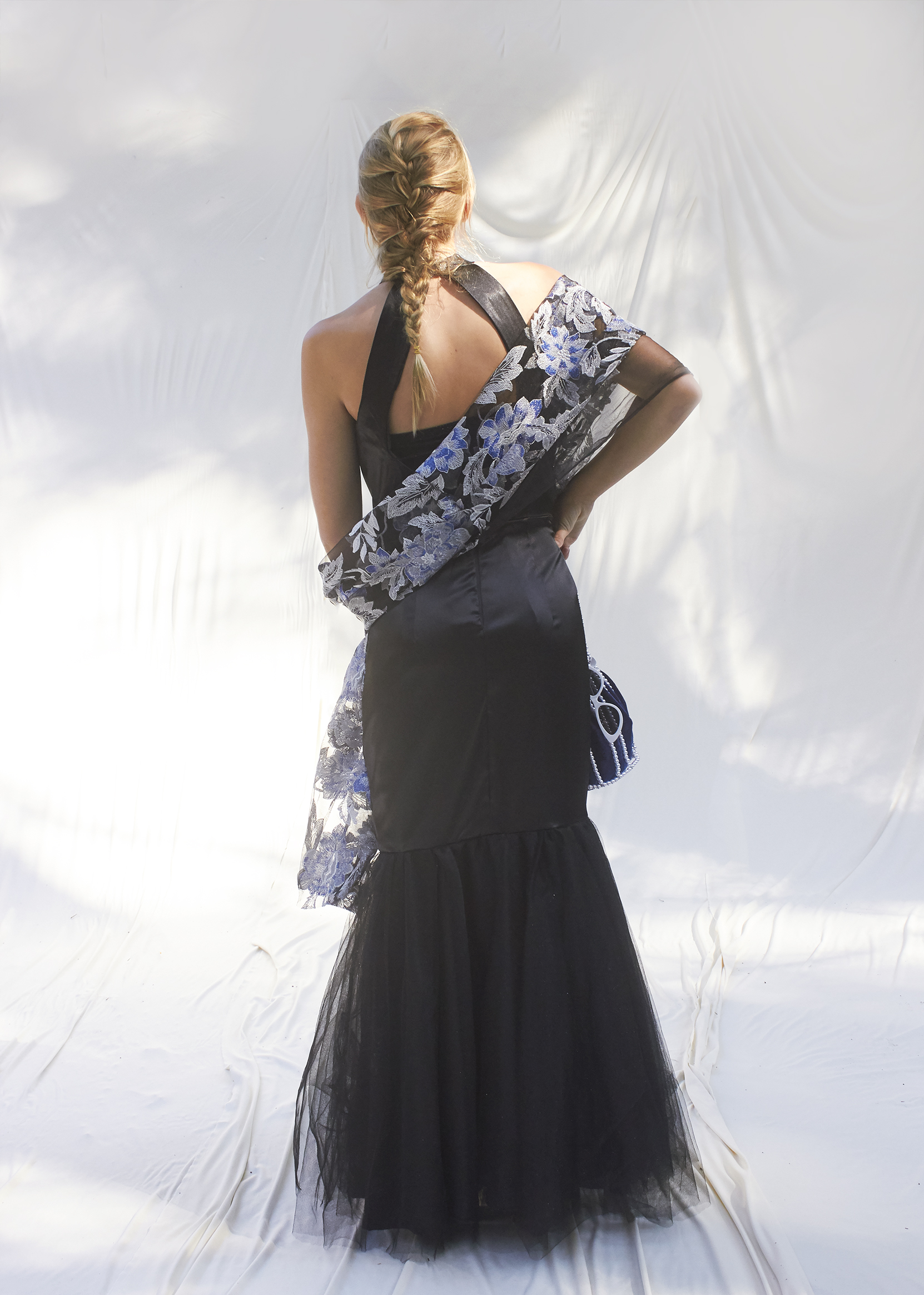 Back view of black halter trumpet gown with draped brocade shawl