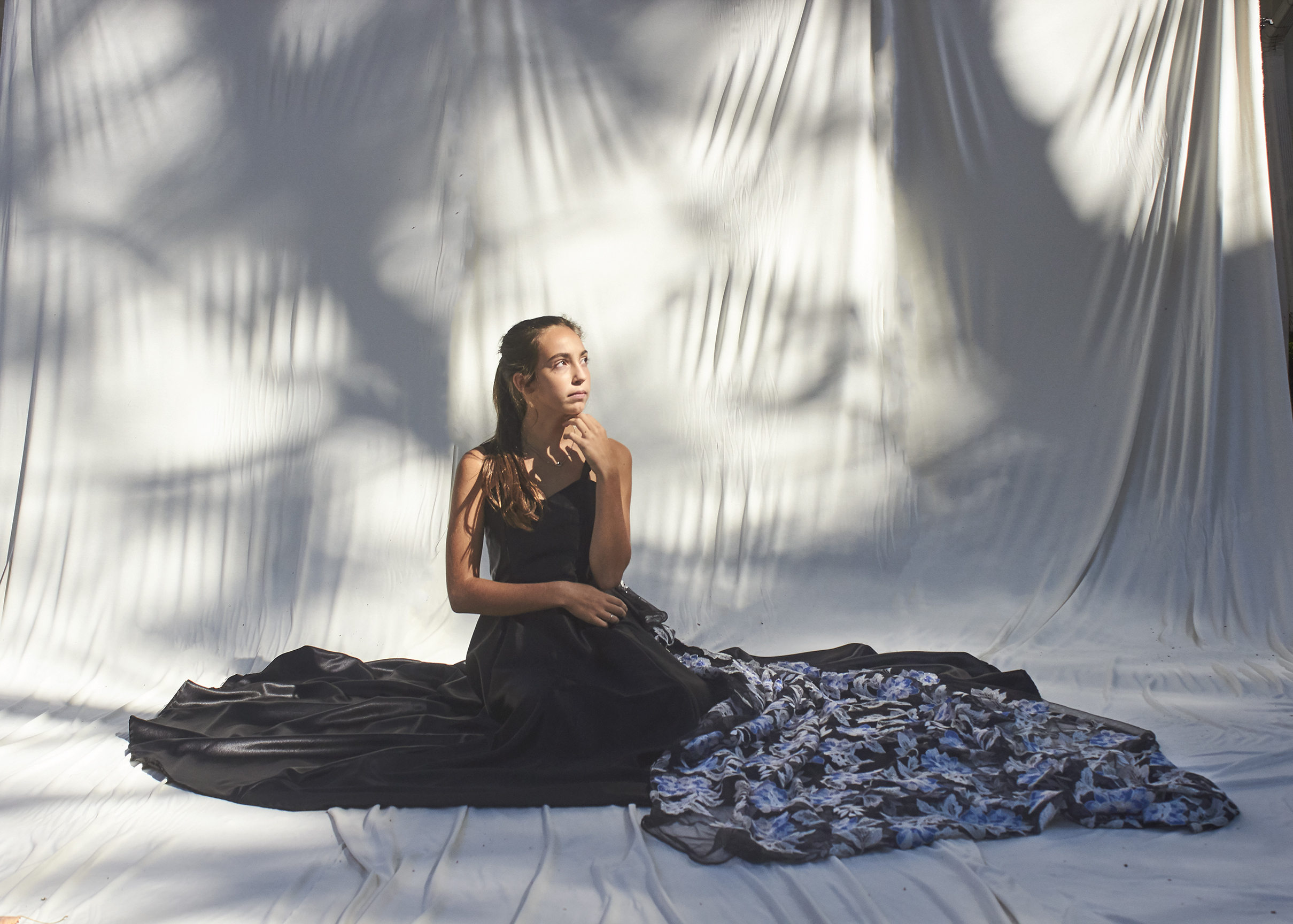 Photo of a girl sitting in big black evening wear gown with a brocade train