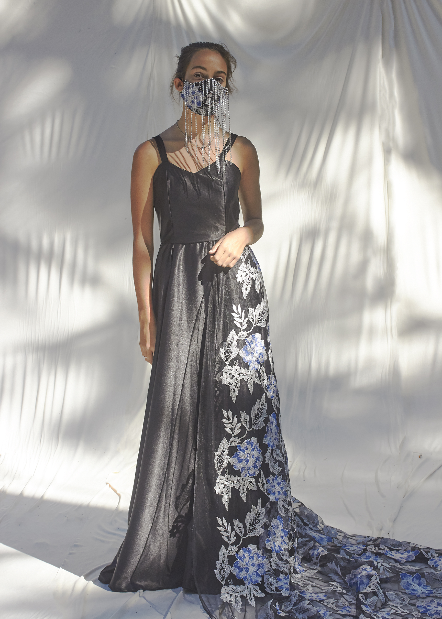 Photo of girl wearing mask in a black elegant gown with a brocade train