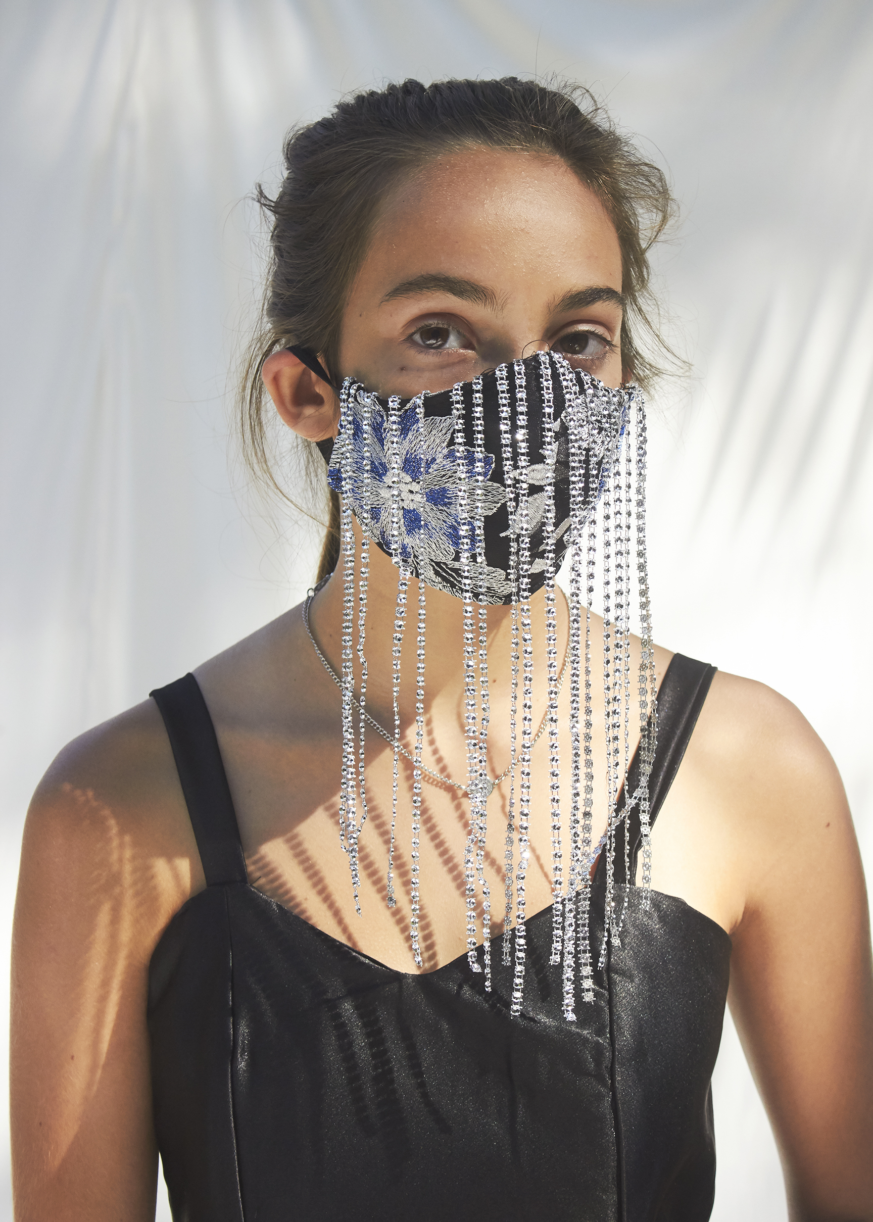 Detail shot of girl standing in black gown with silver sequinface mask on