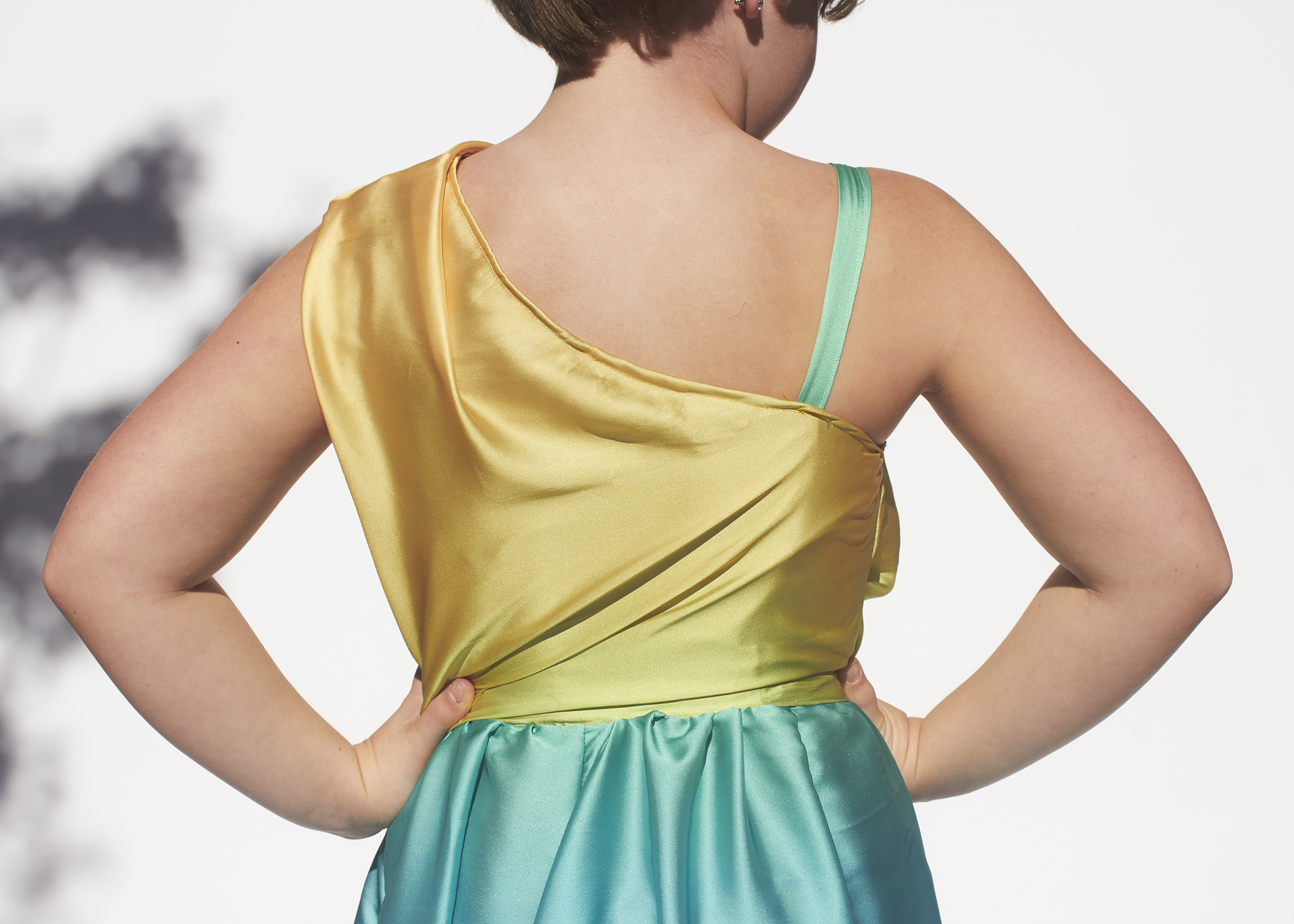 Close up photo of a one shoulder yellow and blue ombre dress