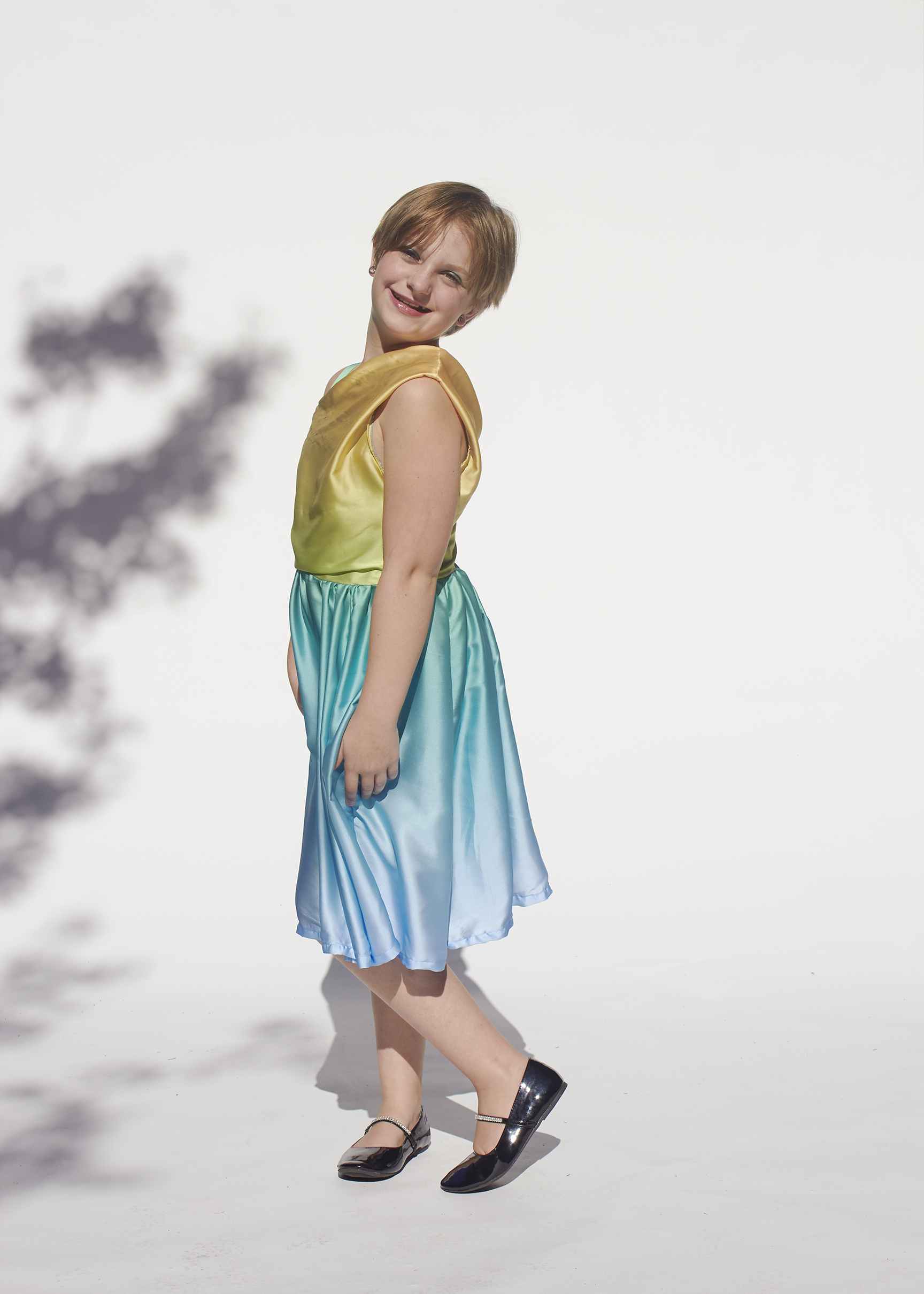 Young girl in a yellow and aqua one shoulder dress