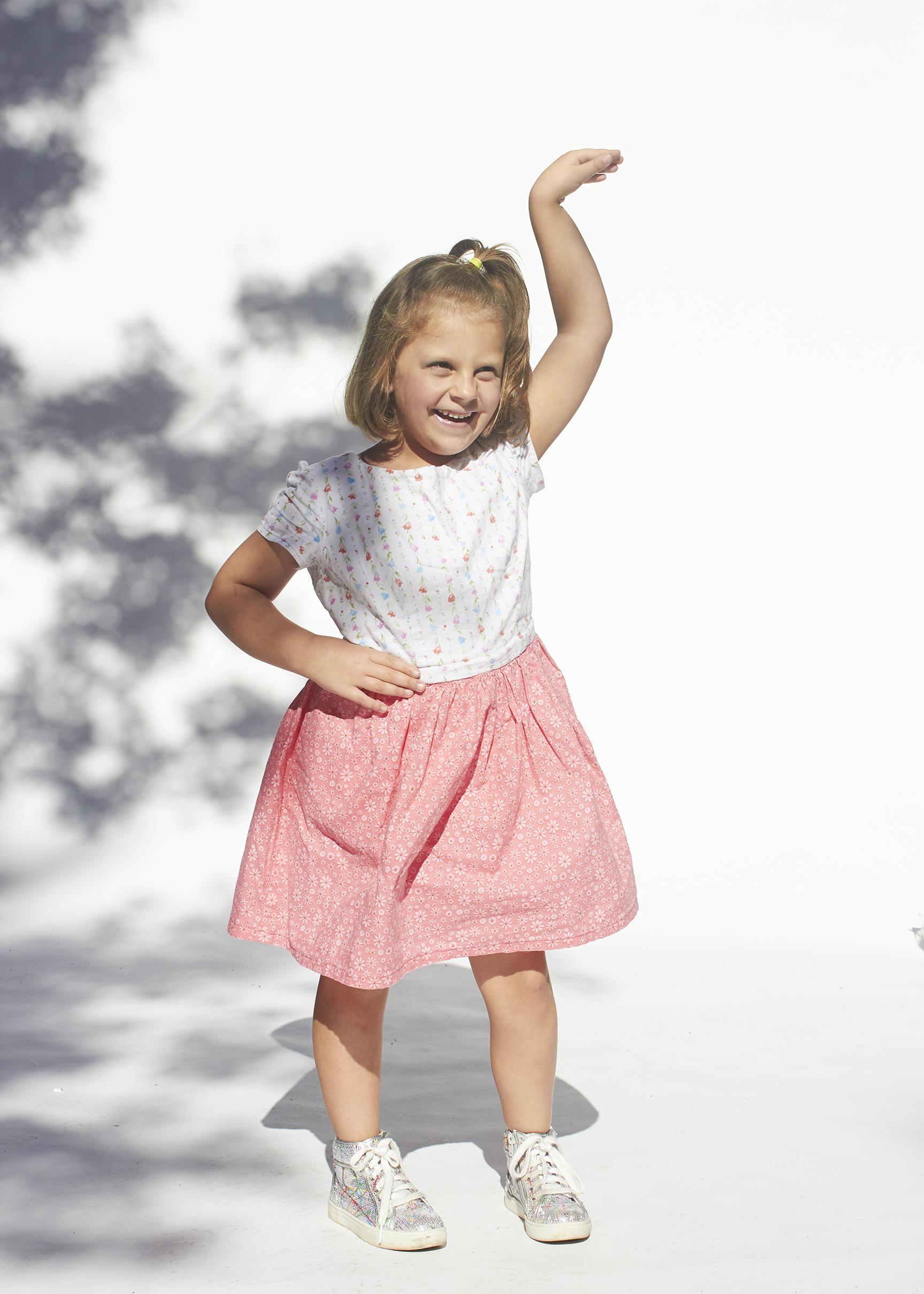 Littler girl posing in a tea cup pose in a white and pink floral dress