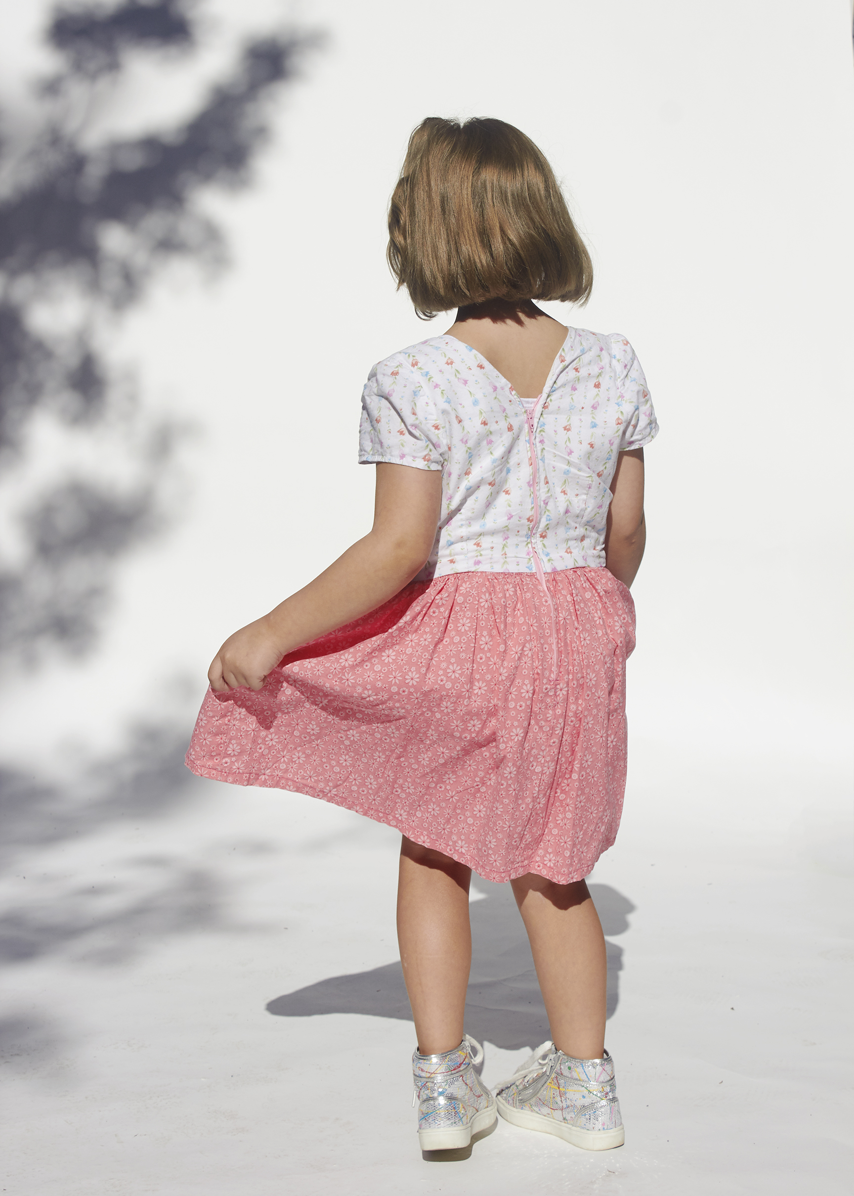 Back view of girl spinning in white and pink dress