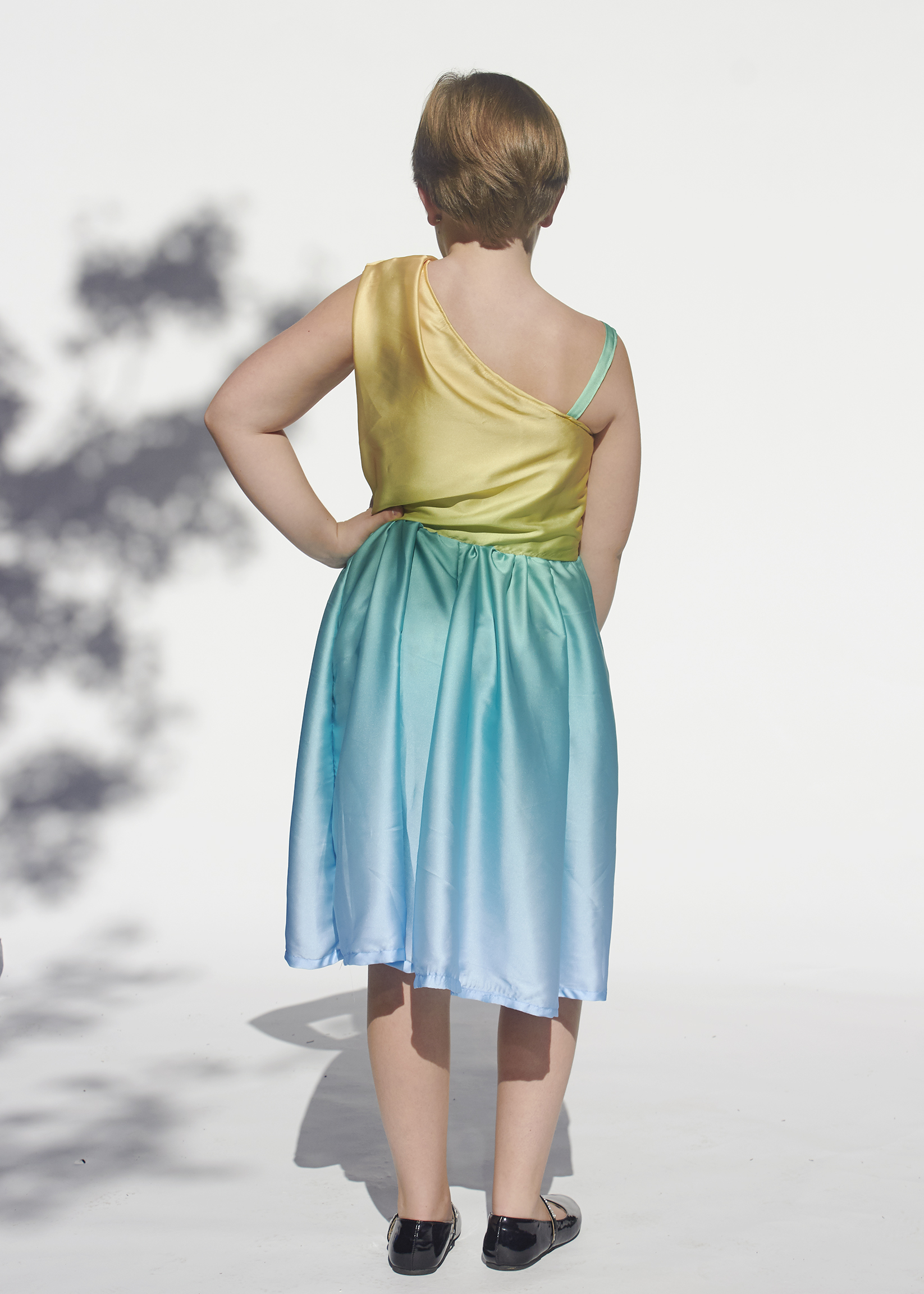 Back view of girl in a one shoulder yellow and blue satin dress