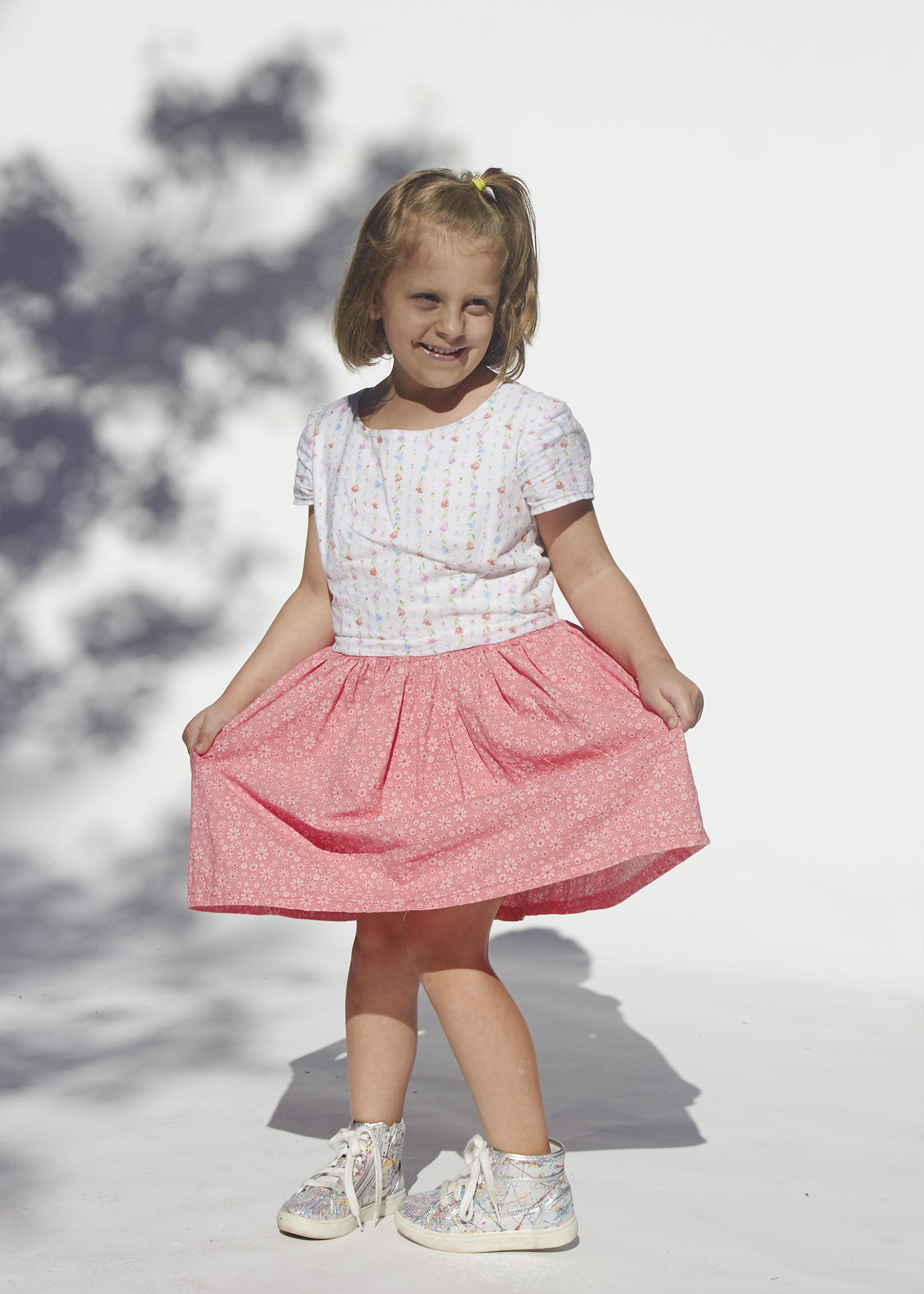 Little girl spinning in floral white and pink dress