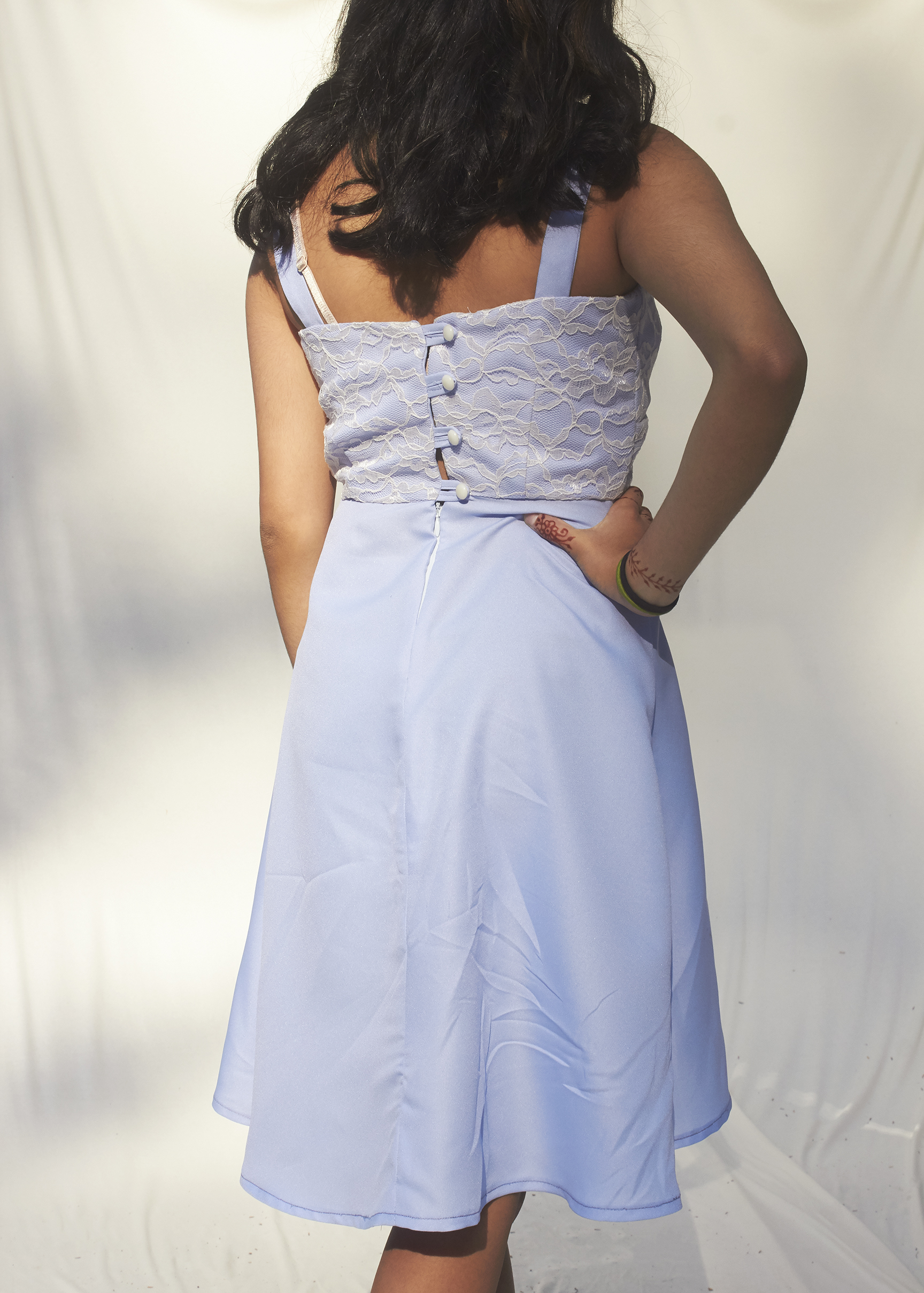 Back View of a buttoned up sky blue lace overlay dress with spaghetti straps.