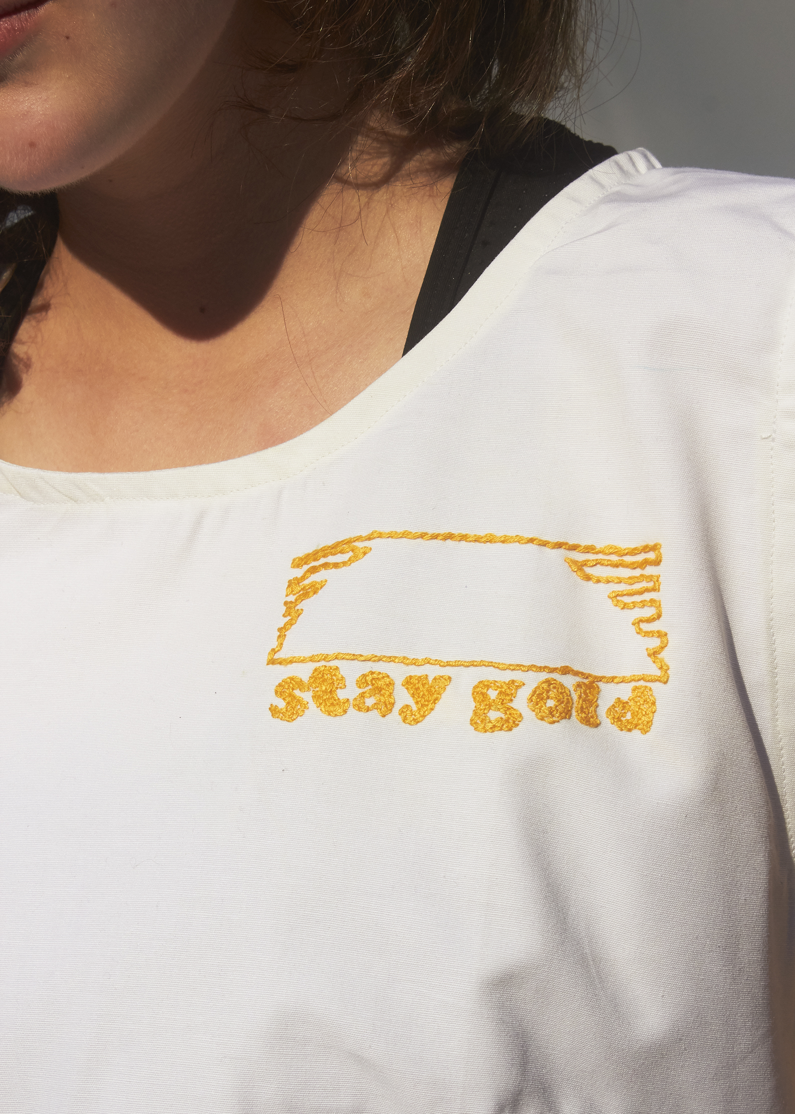 Close up photo of gold embroidery that reads "Stay Gold"