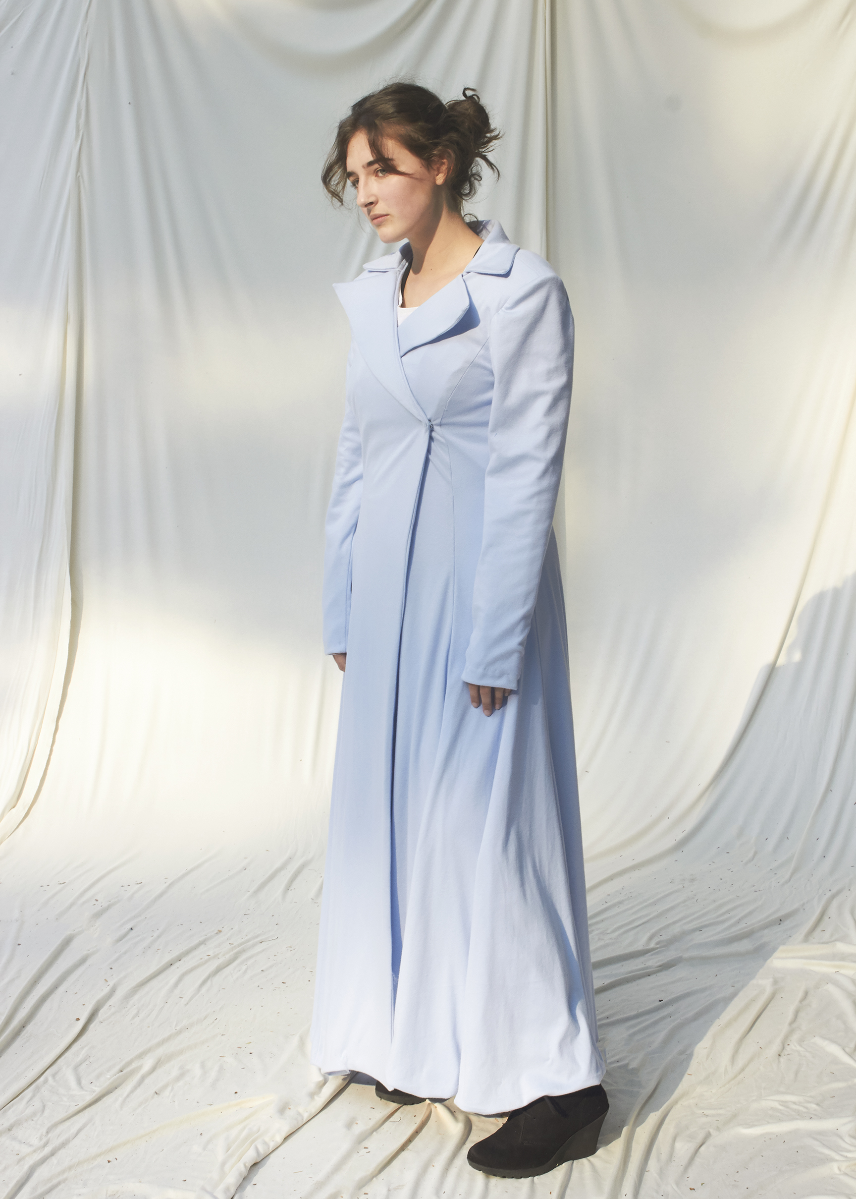 Girl posing in floor length sky blue coat with notched collar