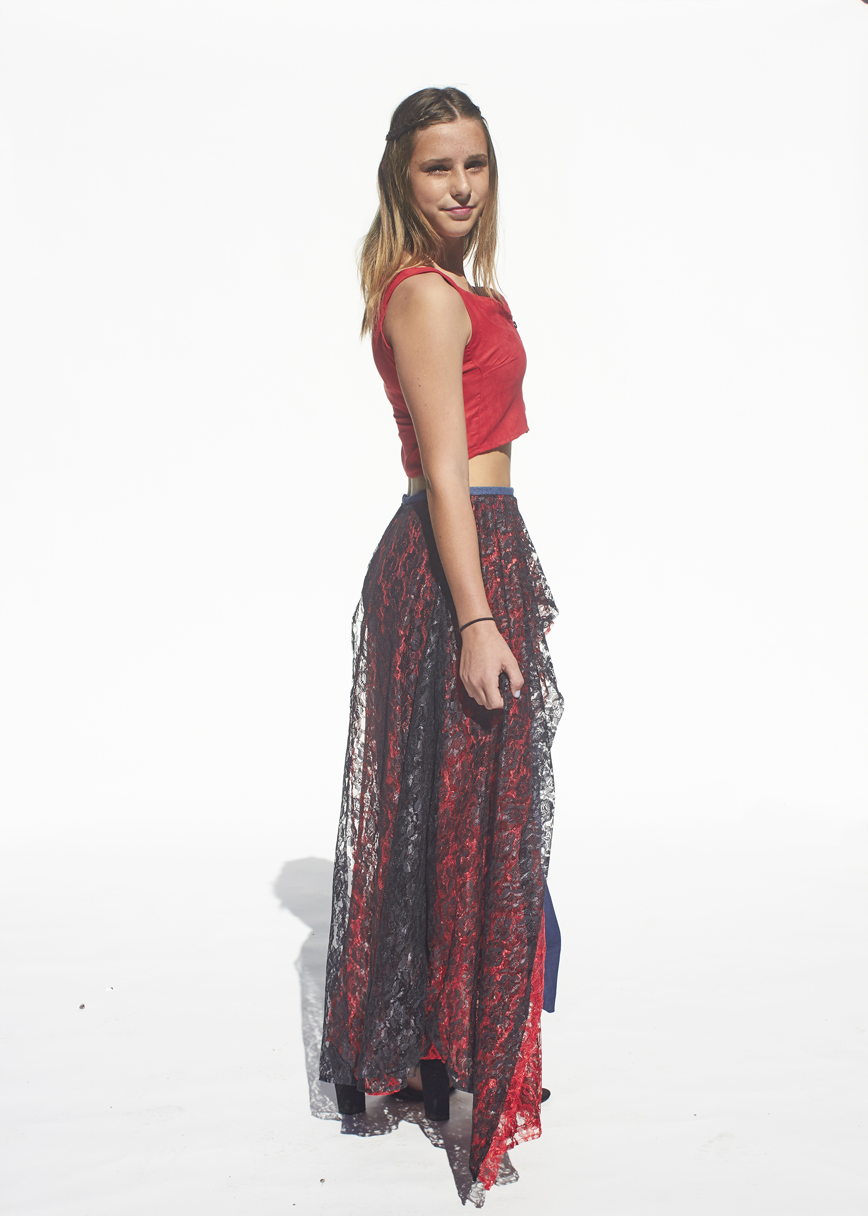 Side view of a red top and red and black lace denim skirt