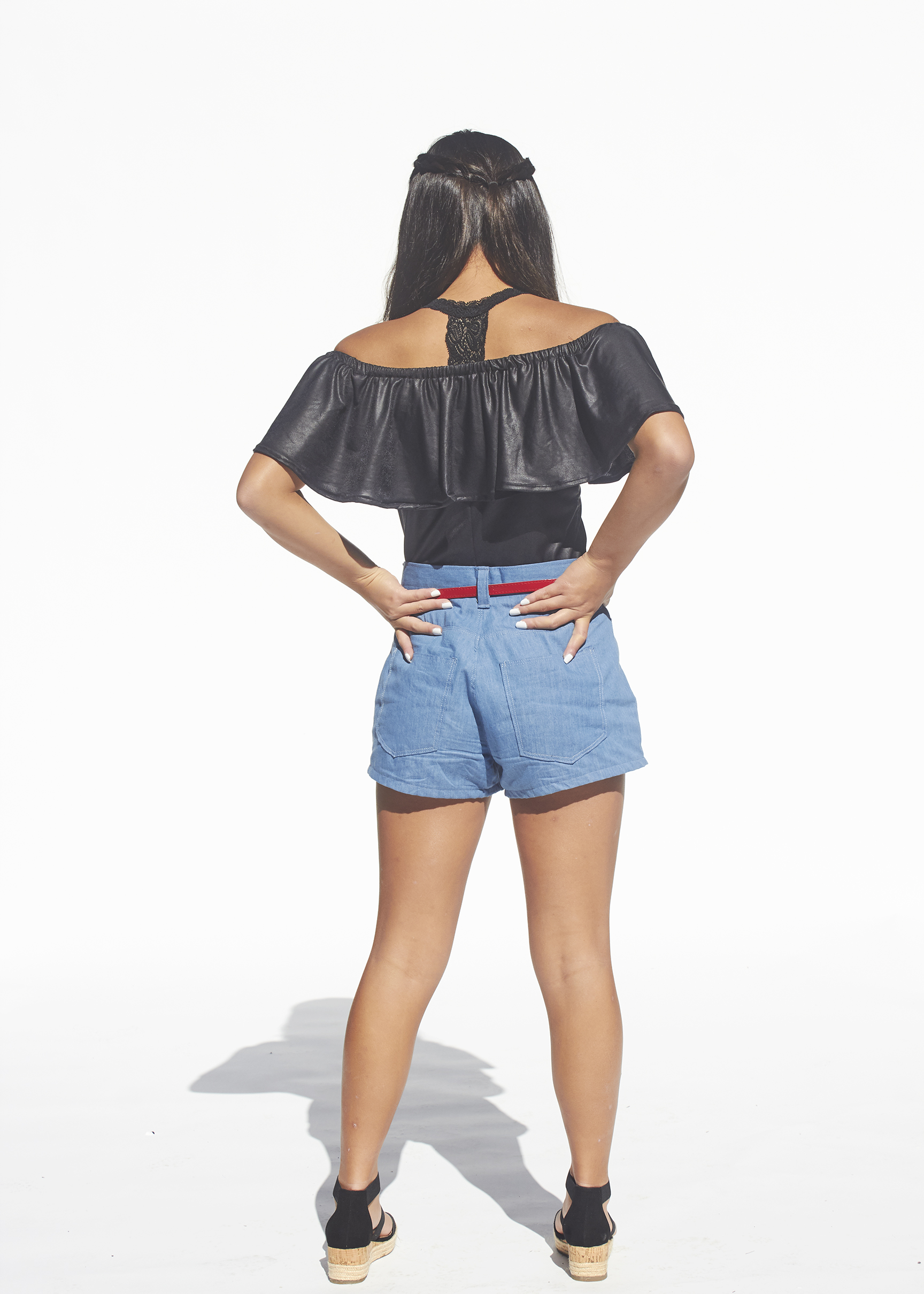 Back view of black flounced top and denim pleated shorts