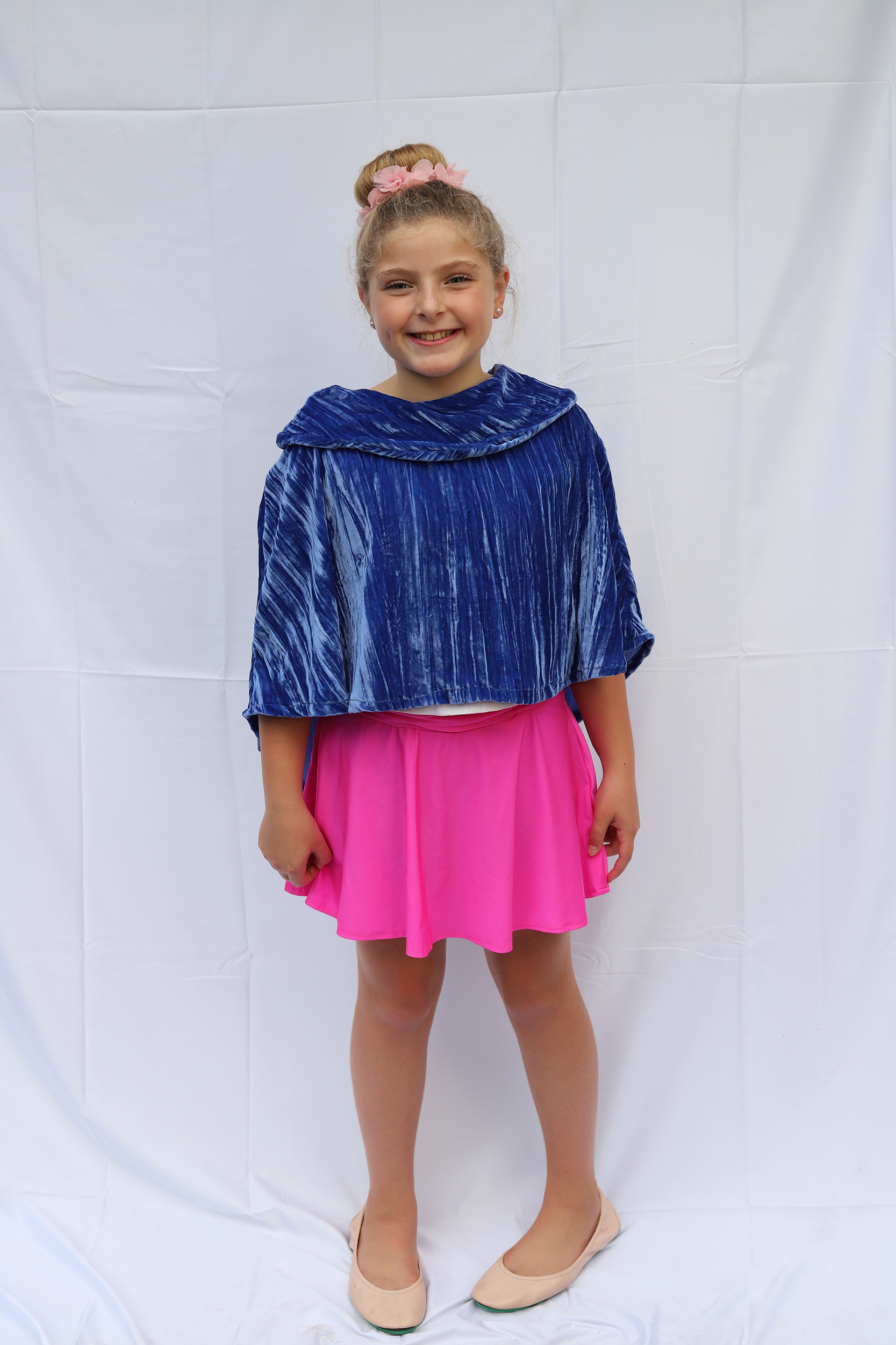 Girl standing in blue velvet cape and hot pink knit skater skirt