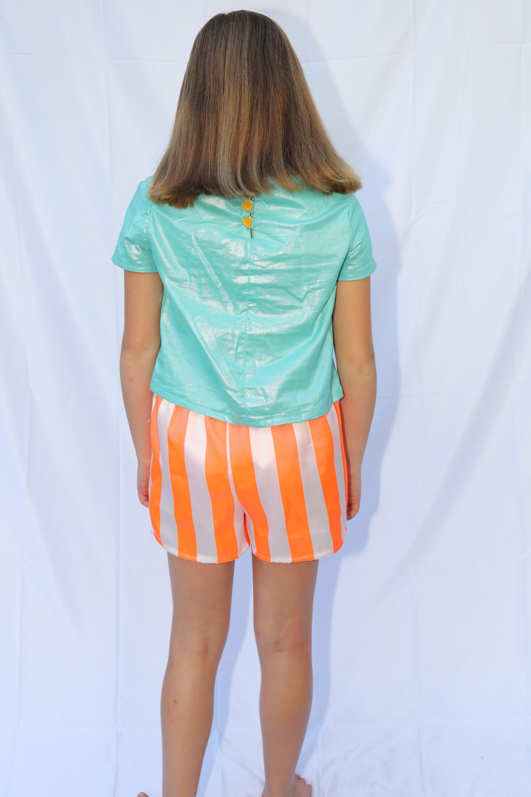 Back view of aqua top and orange and white striped shorts