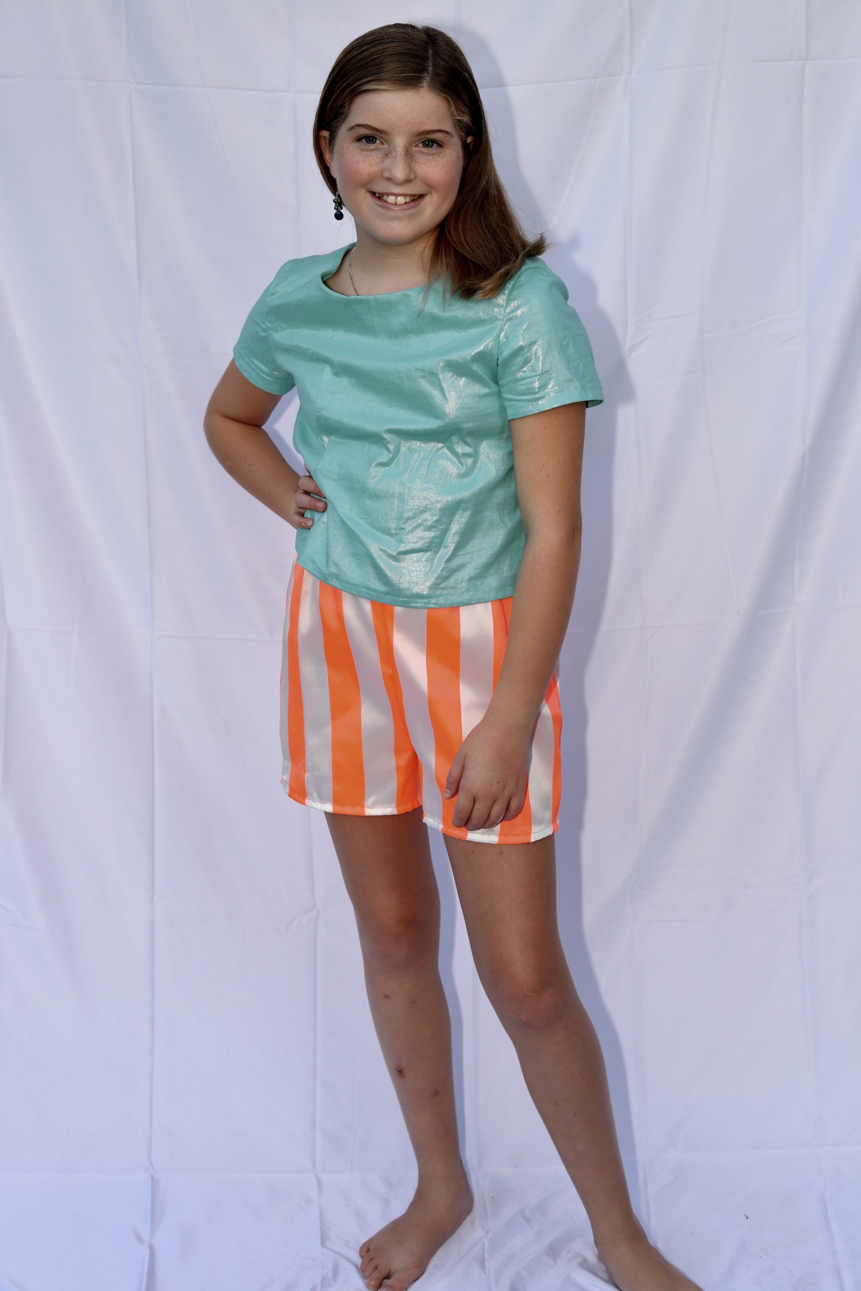 Front view of aqua sparkle top and orange striped shorts