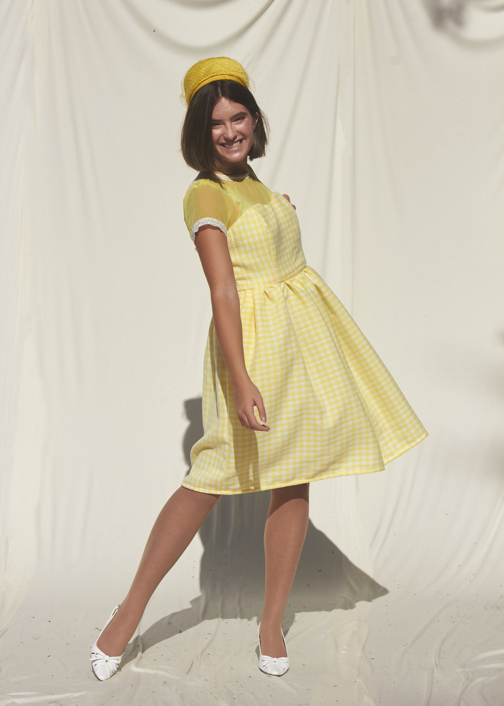 Model posing in gathered 50s gingham yellow dress