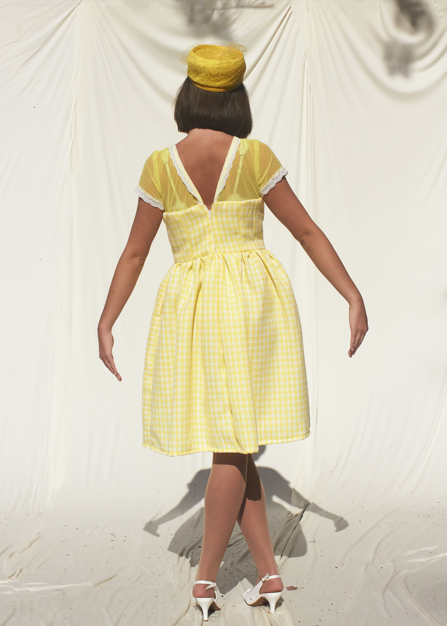 Back view of a 50s style yellow gingham dress with sheer top