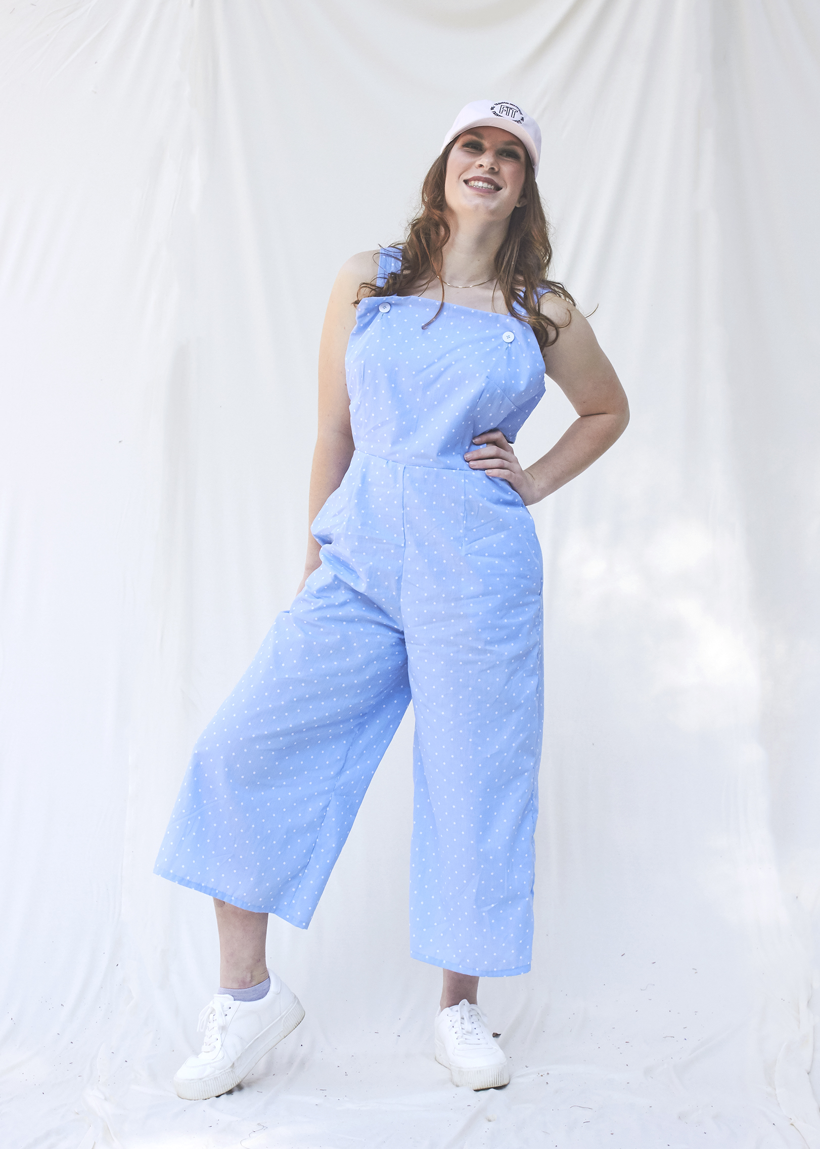 Teenage girl poses with her hand on her hip in a light blue cut out jumpsuit