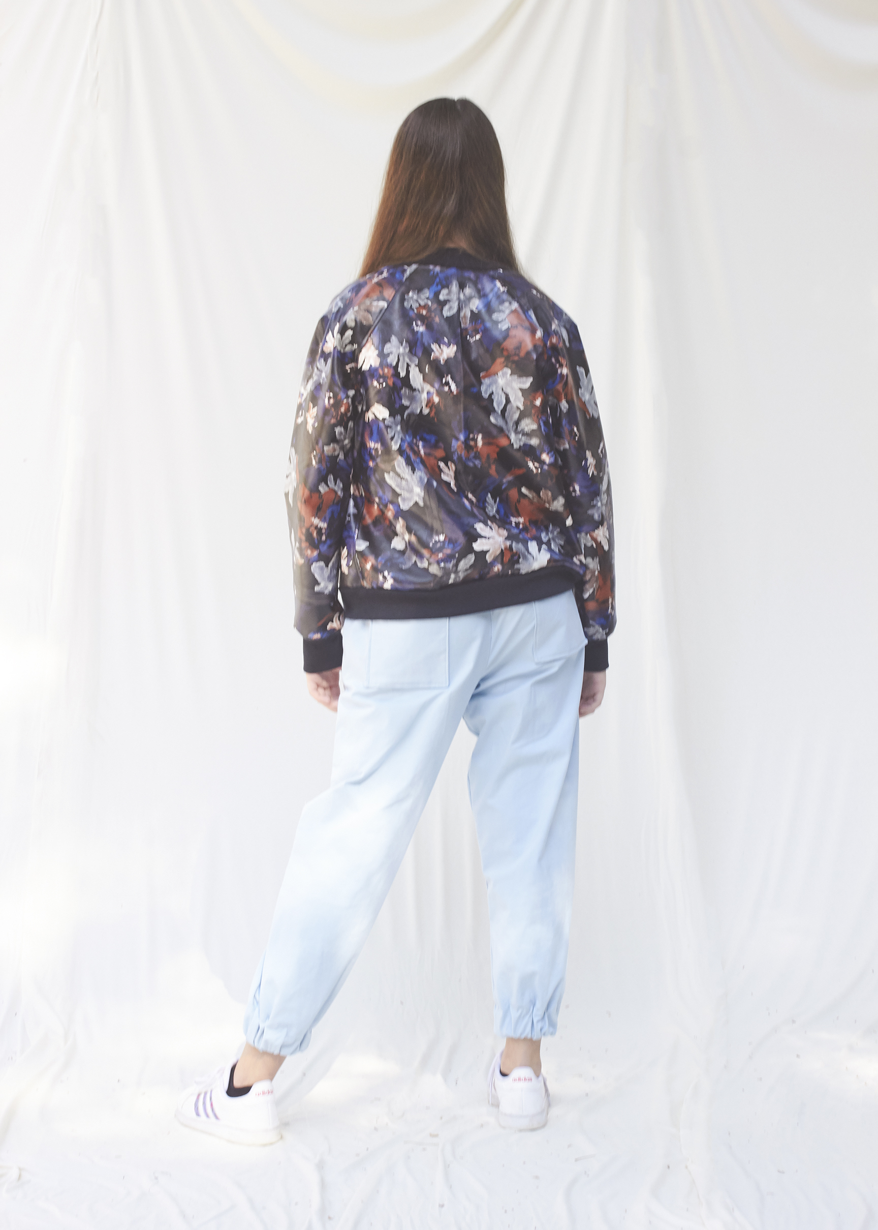 back view of a floral pleather jacket and blue cargo pants