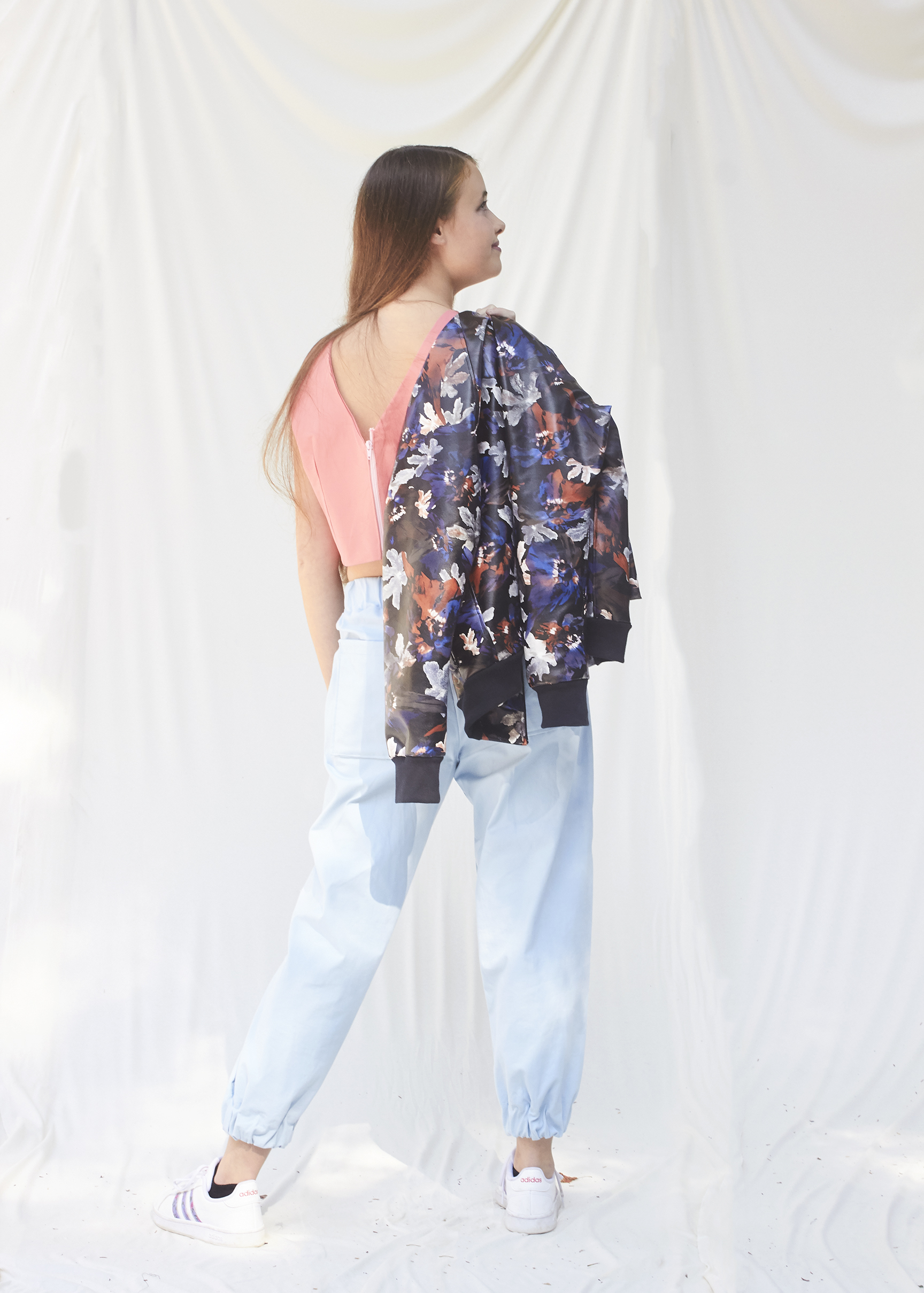 Girl draping a floral pleather bomber jacker over her shoulder