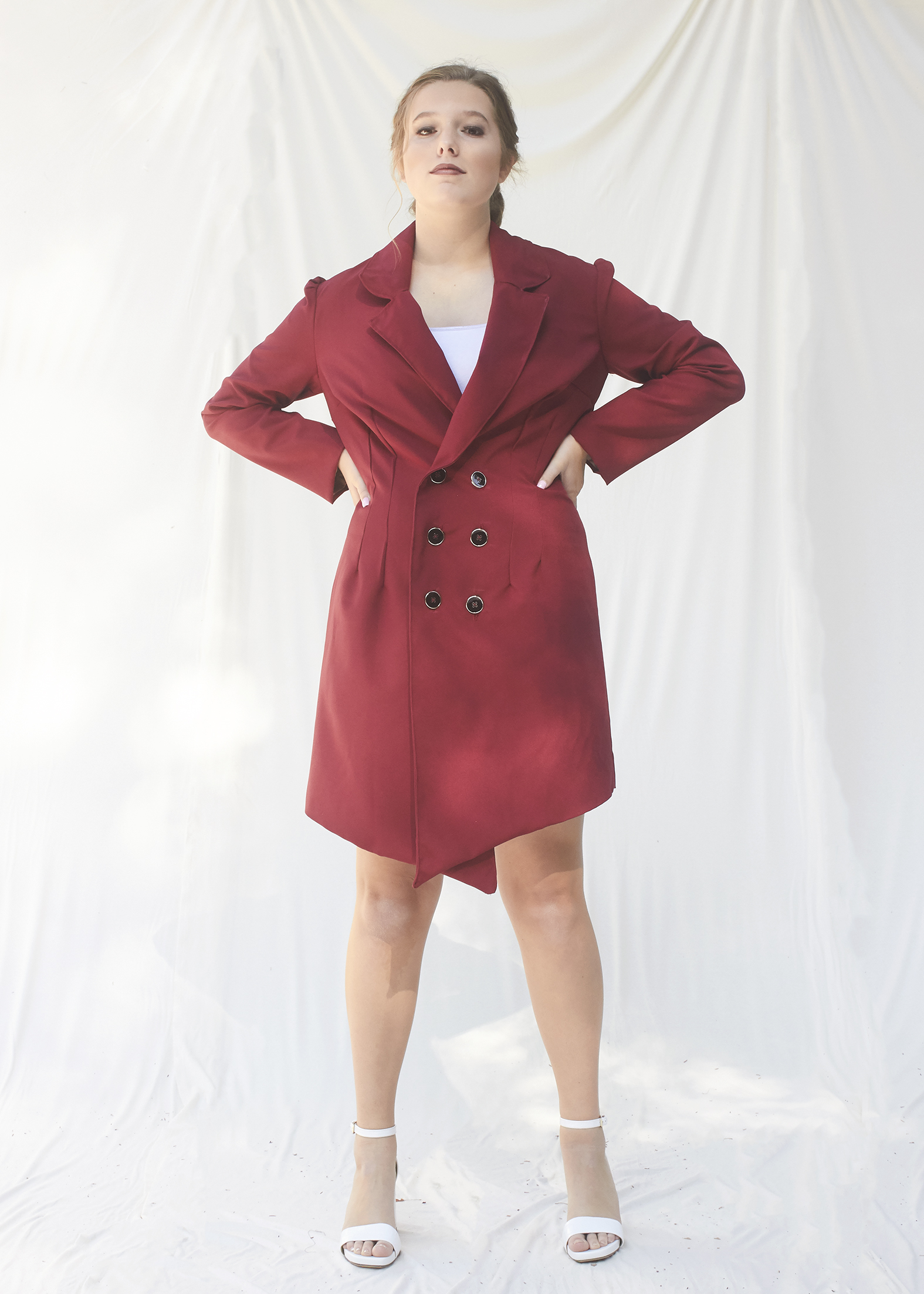 Woman stands in a burgundy power suit dress