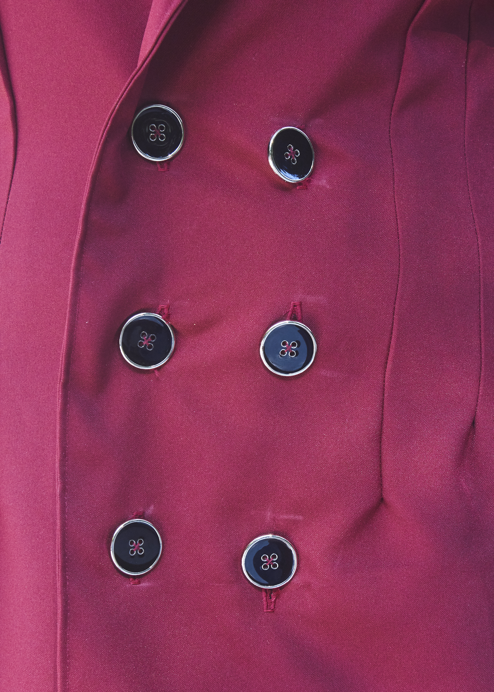 Photo of six black buttons on a burgundy suit