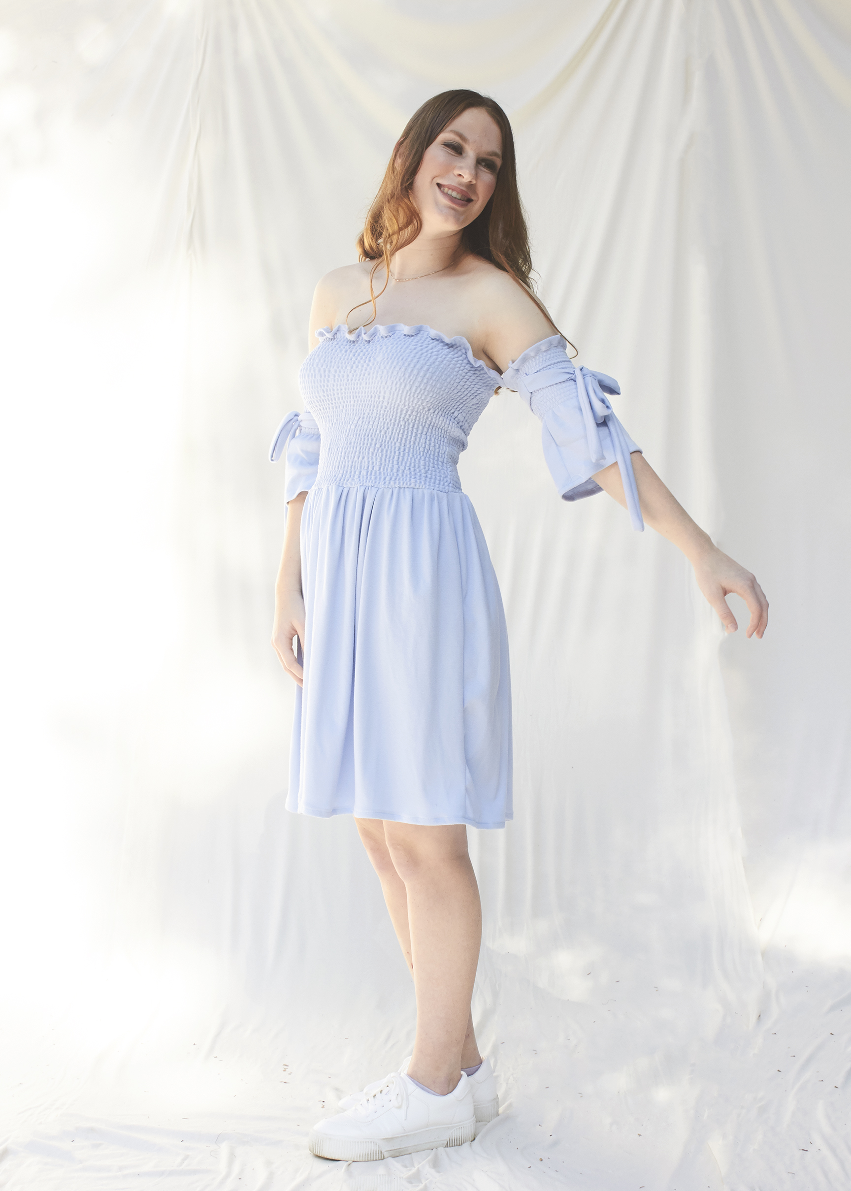 Side view of girl posing in sky blue ruched dress