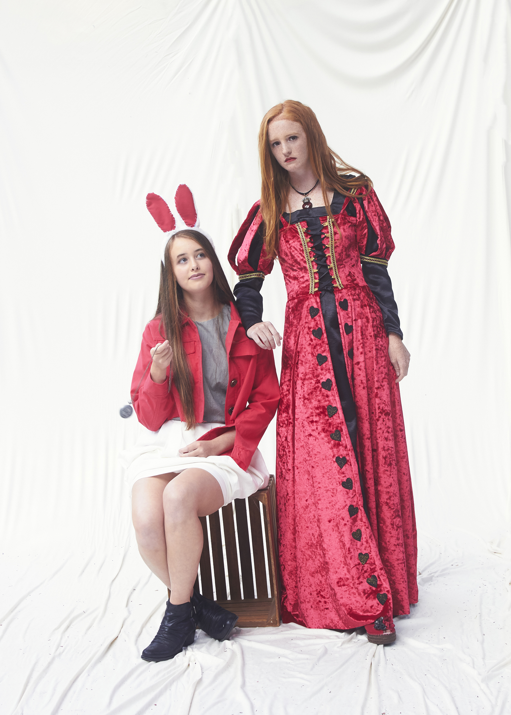 Girl dress Queen of hearts leaning on girl dressed white rabbit