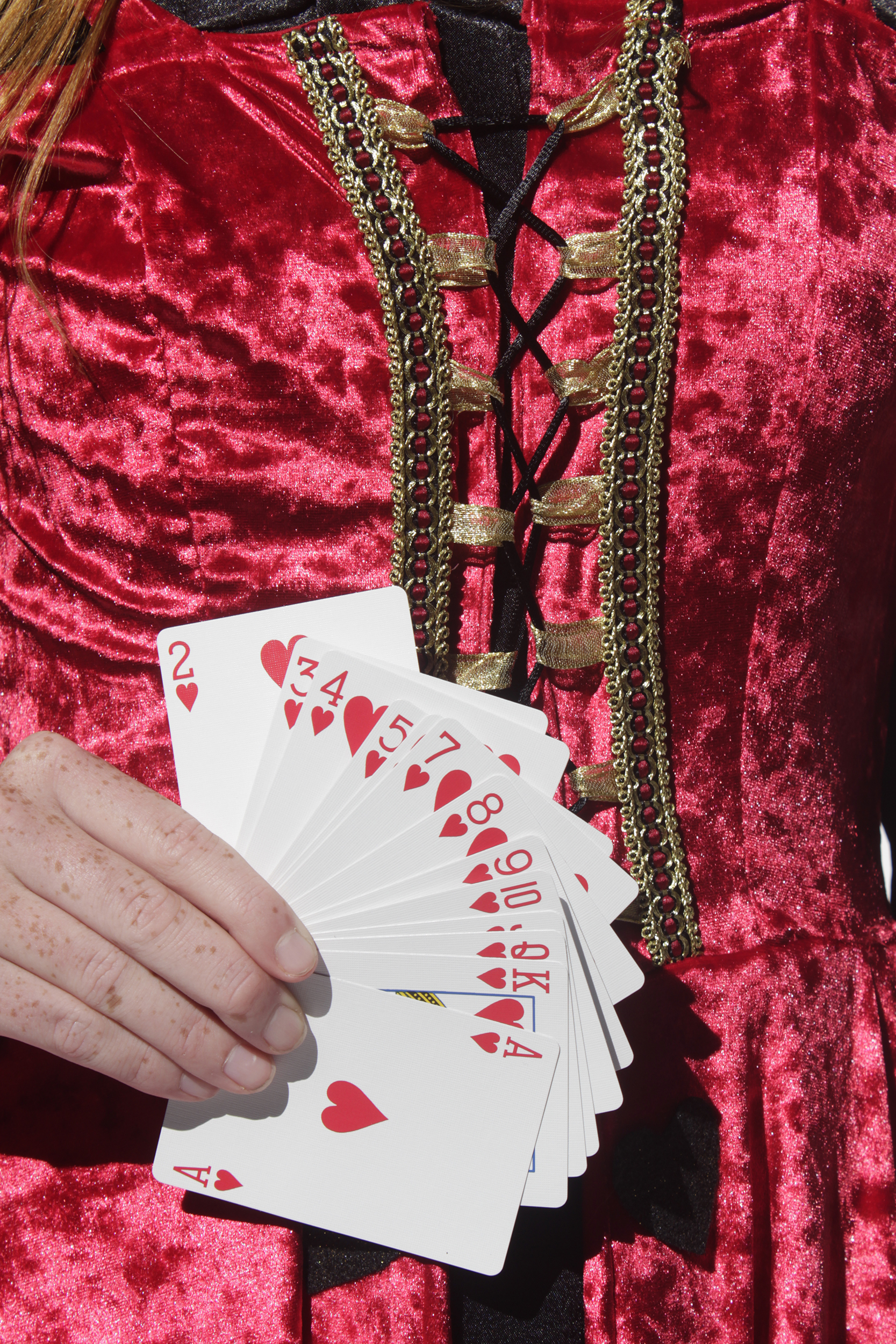 Close up view of red corset with a deck of card in the. models hand