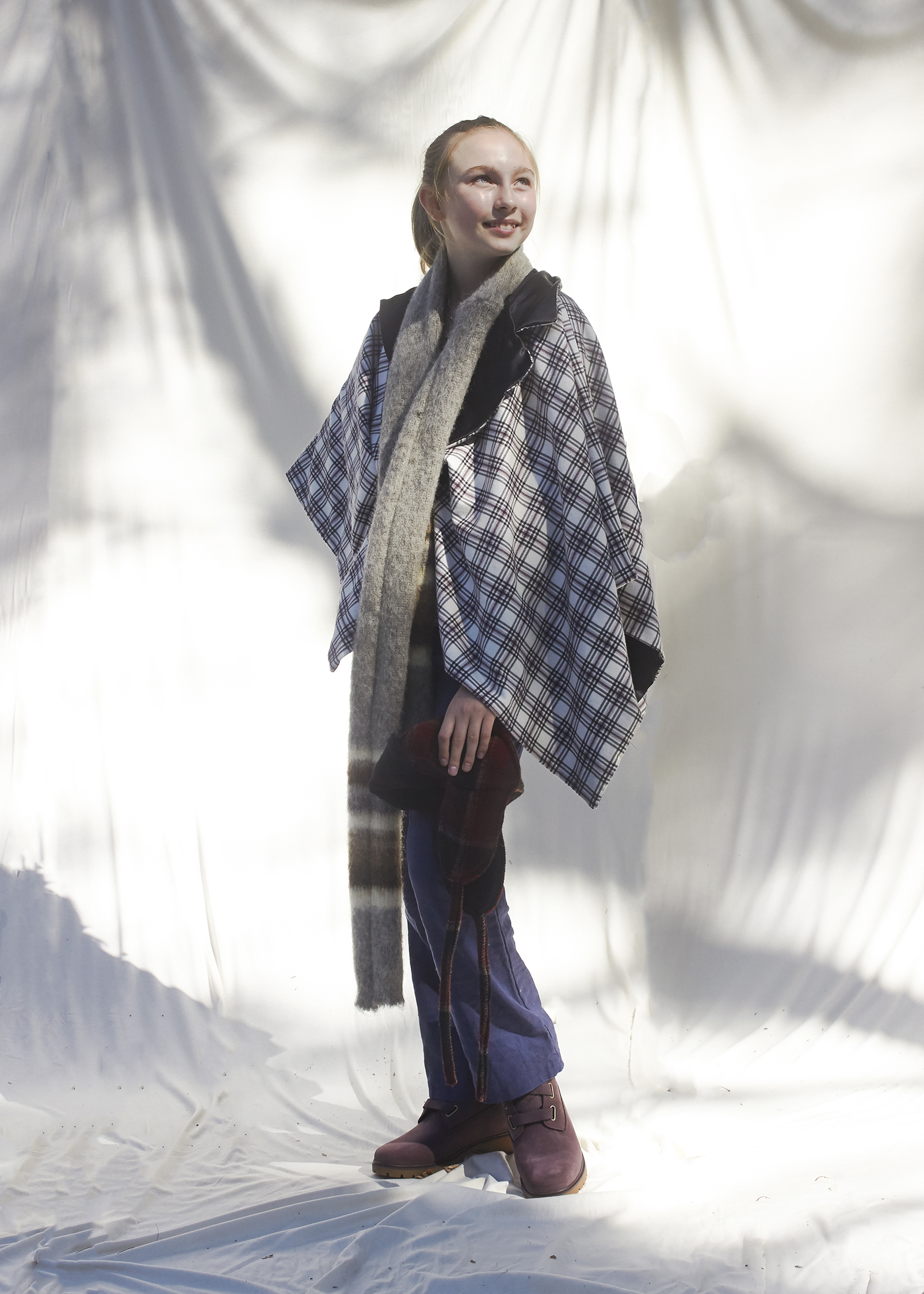 Young girl standing wearing a poncho and scarf that she sewed herself