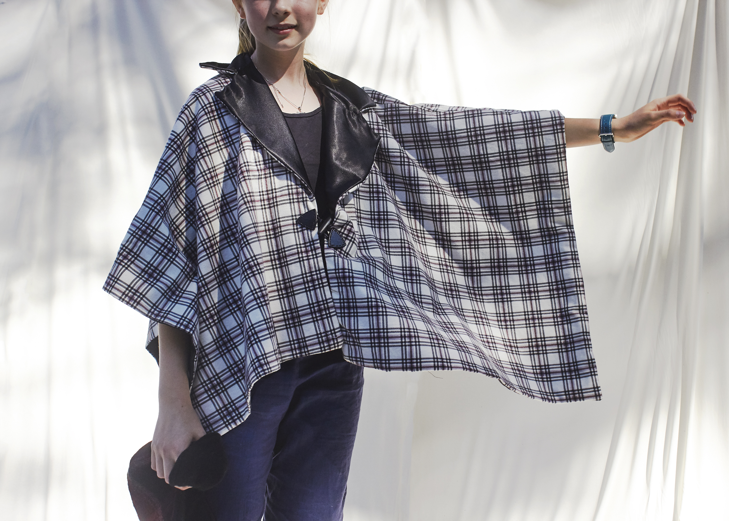 Close up photo of young girl in winter plaid black and white poncho