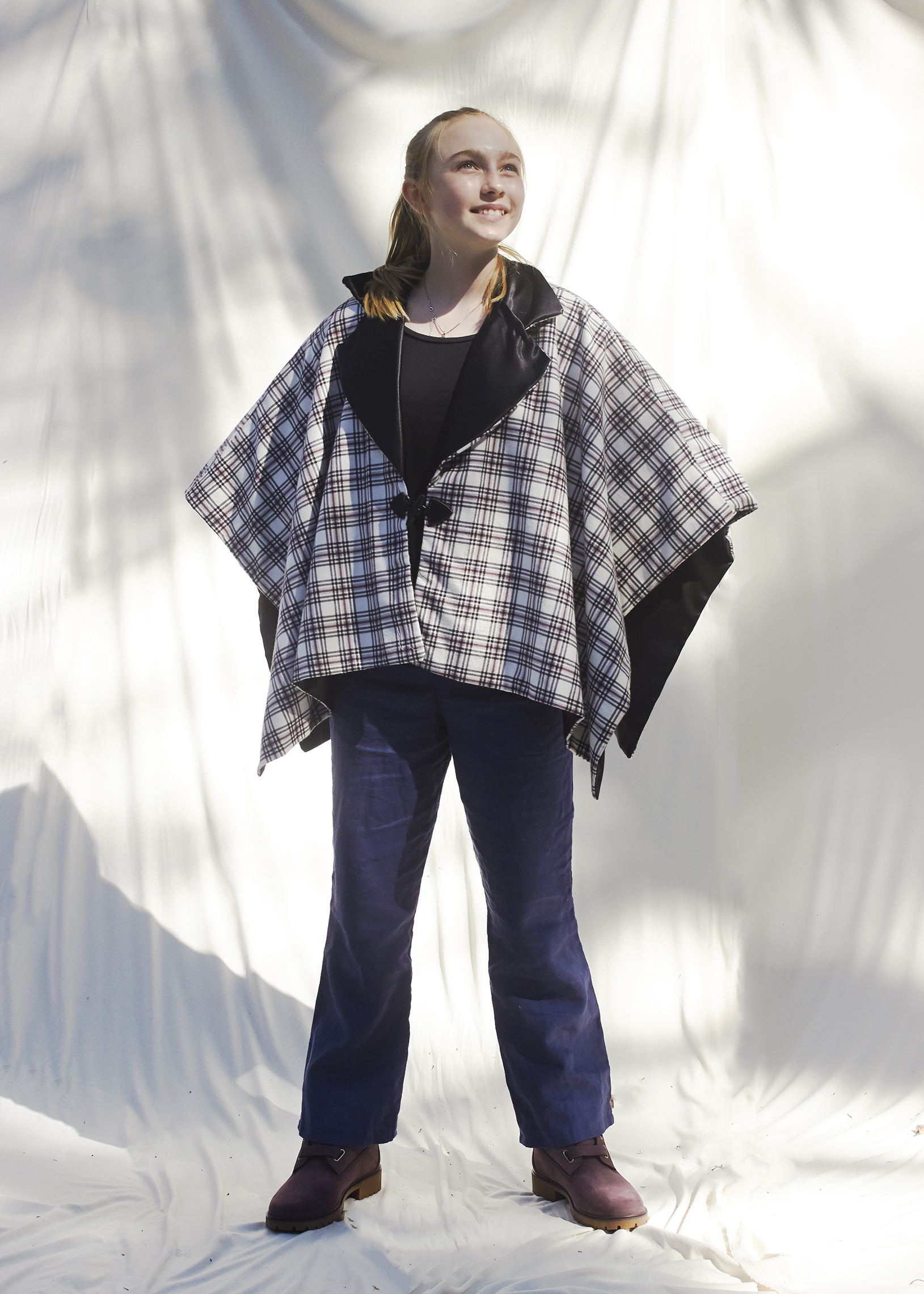 Young girl standing in winter black and white plaid poncho.