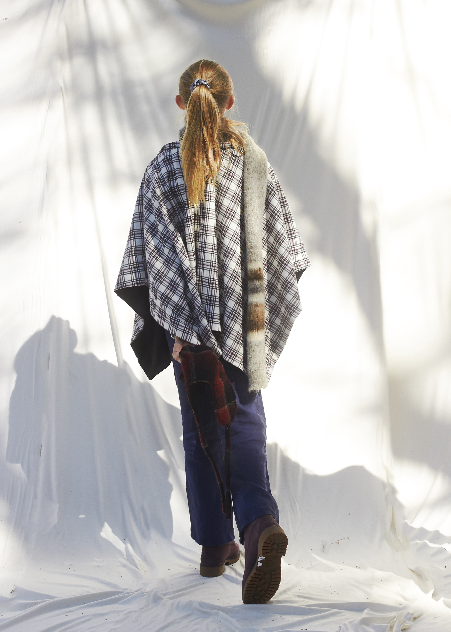 Young girl walking away from camera in a winter poncho and scarf