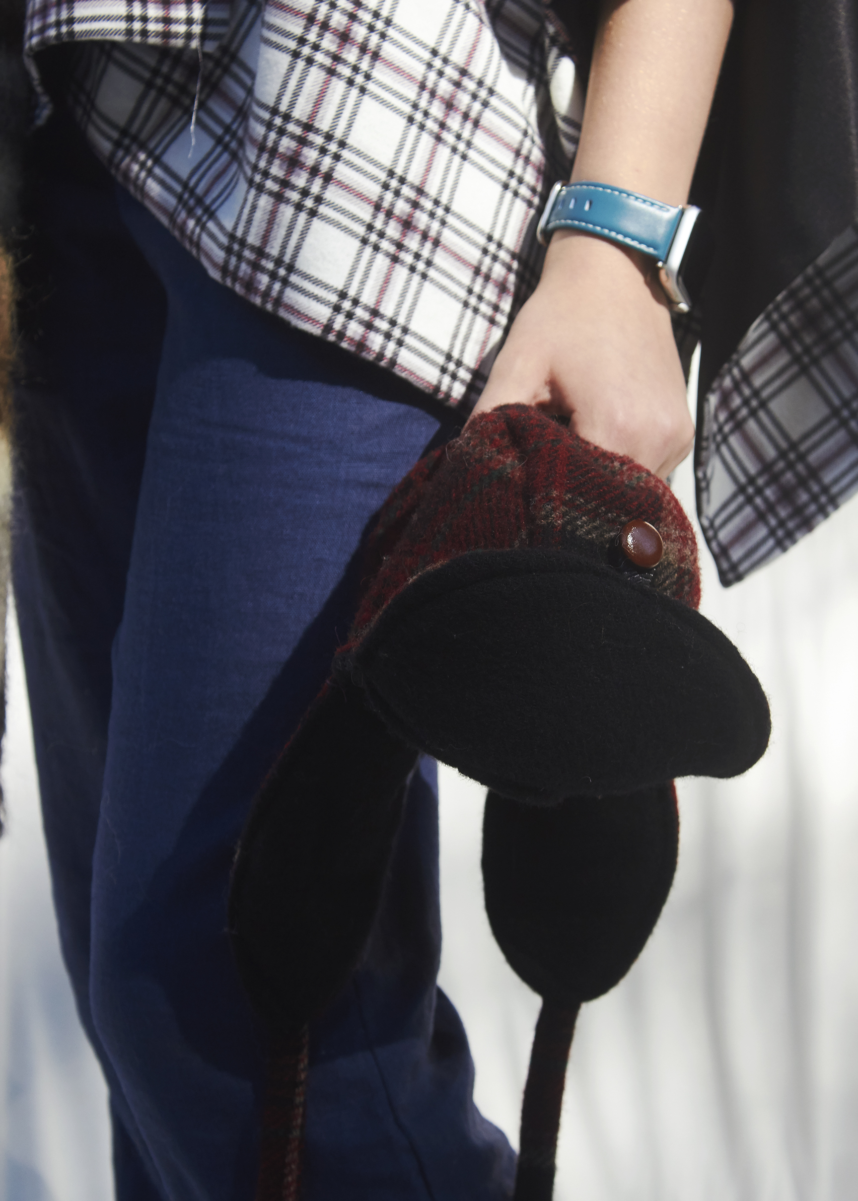 Girl holds a red plaid trapper hat that is lined in black fleece