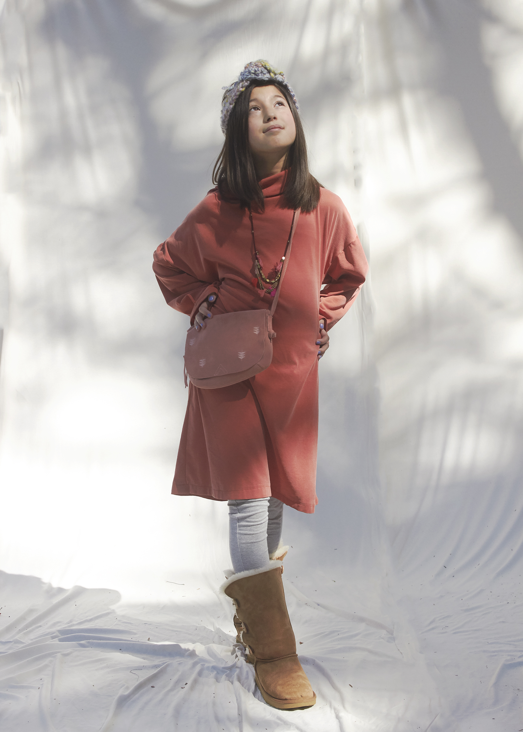 Young girl standing in burnt orange/ rust long sleeve turtle neck sweater dress