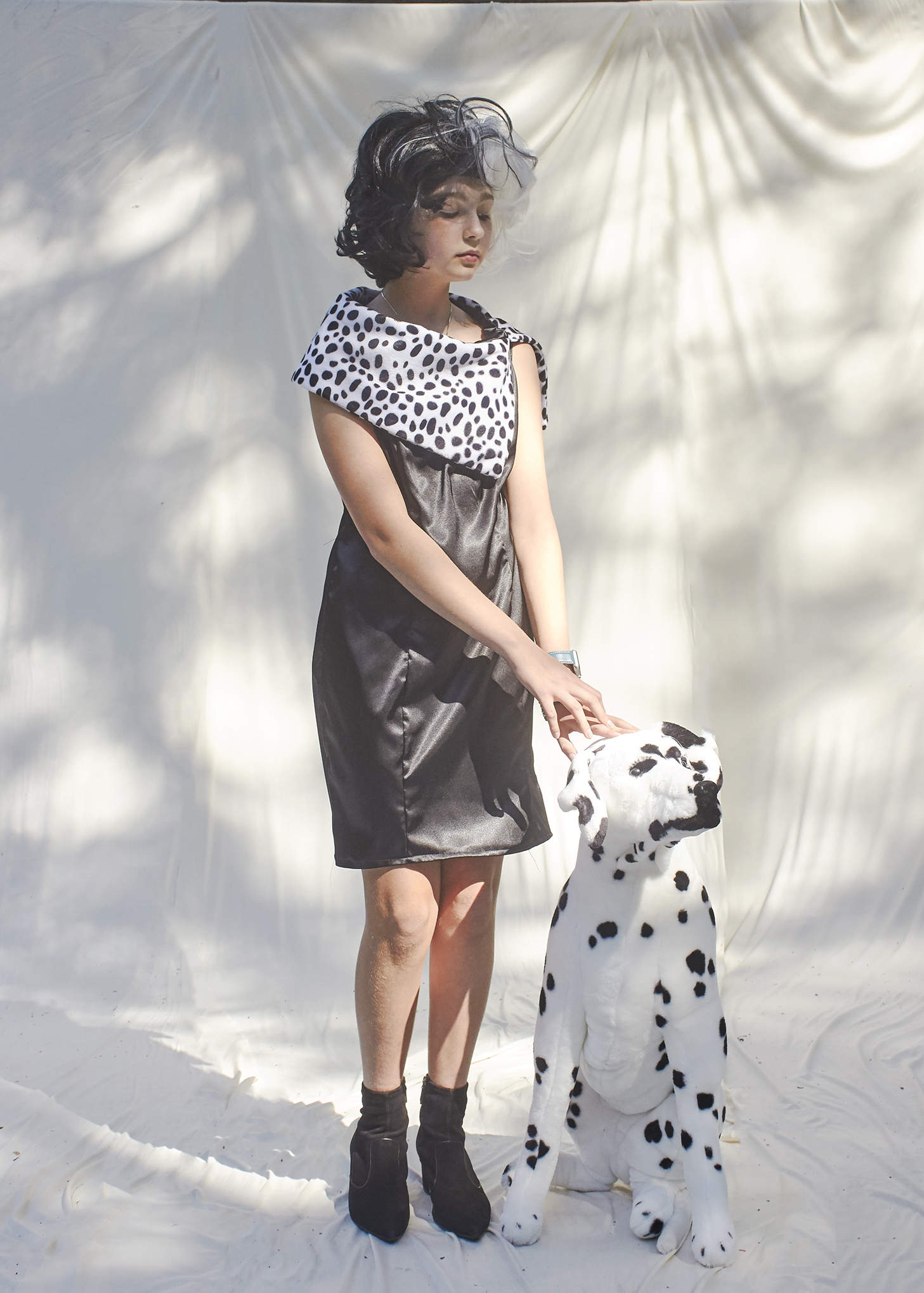 Girl posing in black satin dress with fur trim holding a stuffed toy Dalmatian