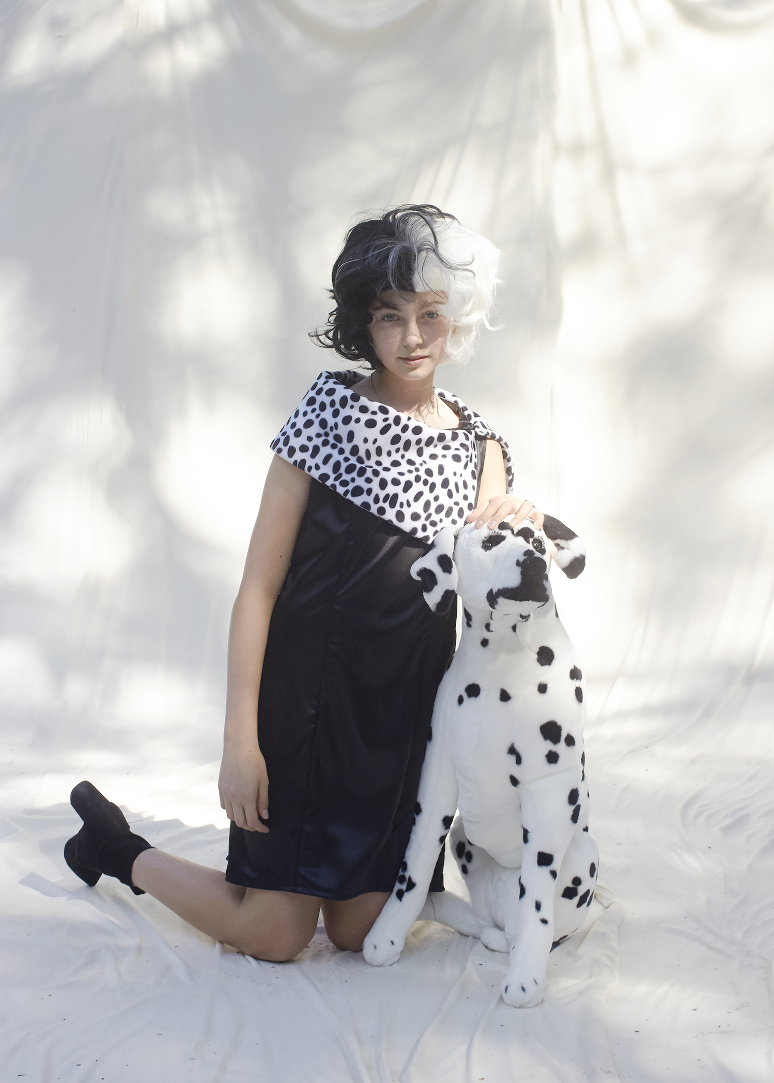 Photo of Girl in Cruella Deville costume with a fake Dalmatian