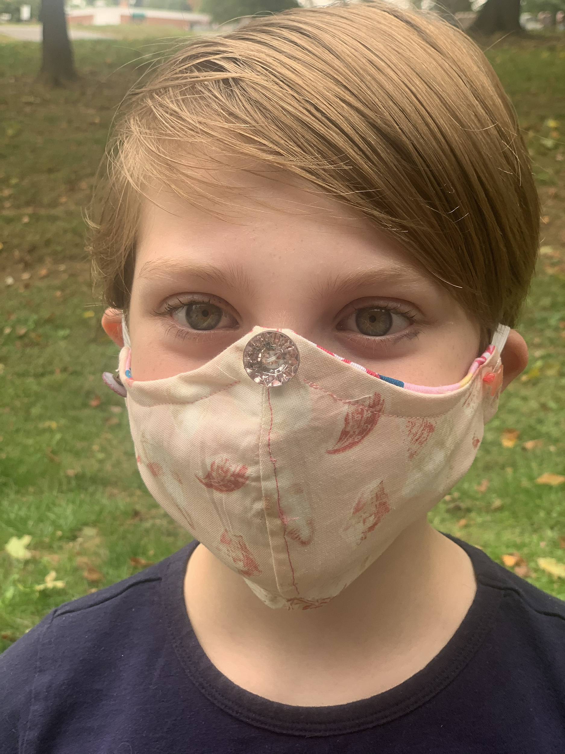 Front view of girl wearing sea shell face mask with button on the nose